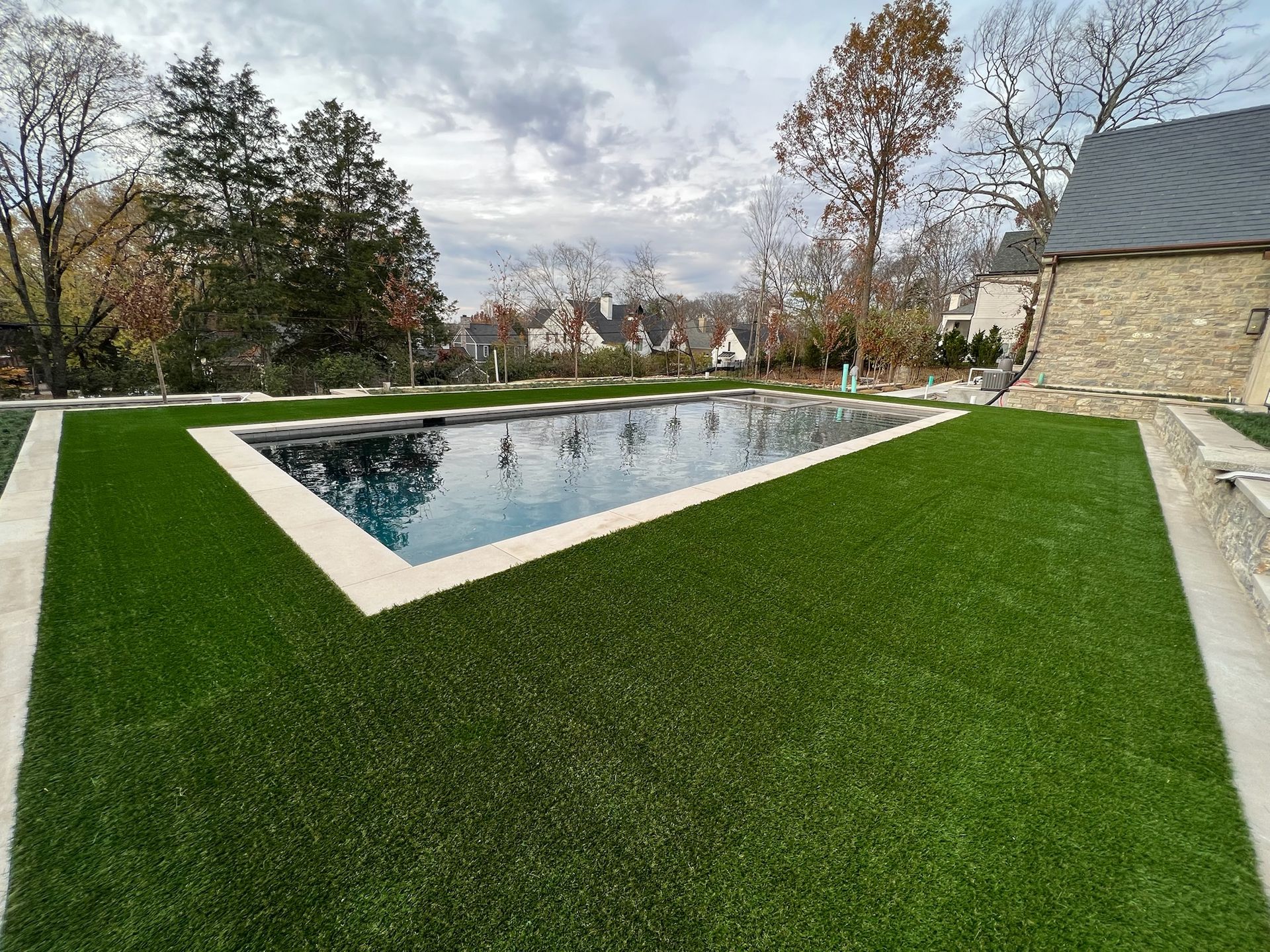 A large swimming pool surrounded by green grass in a backyard.