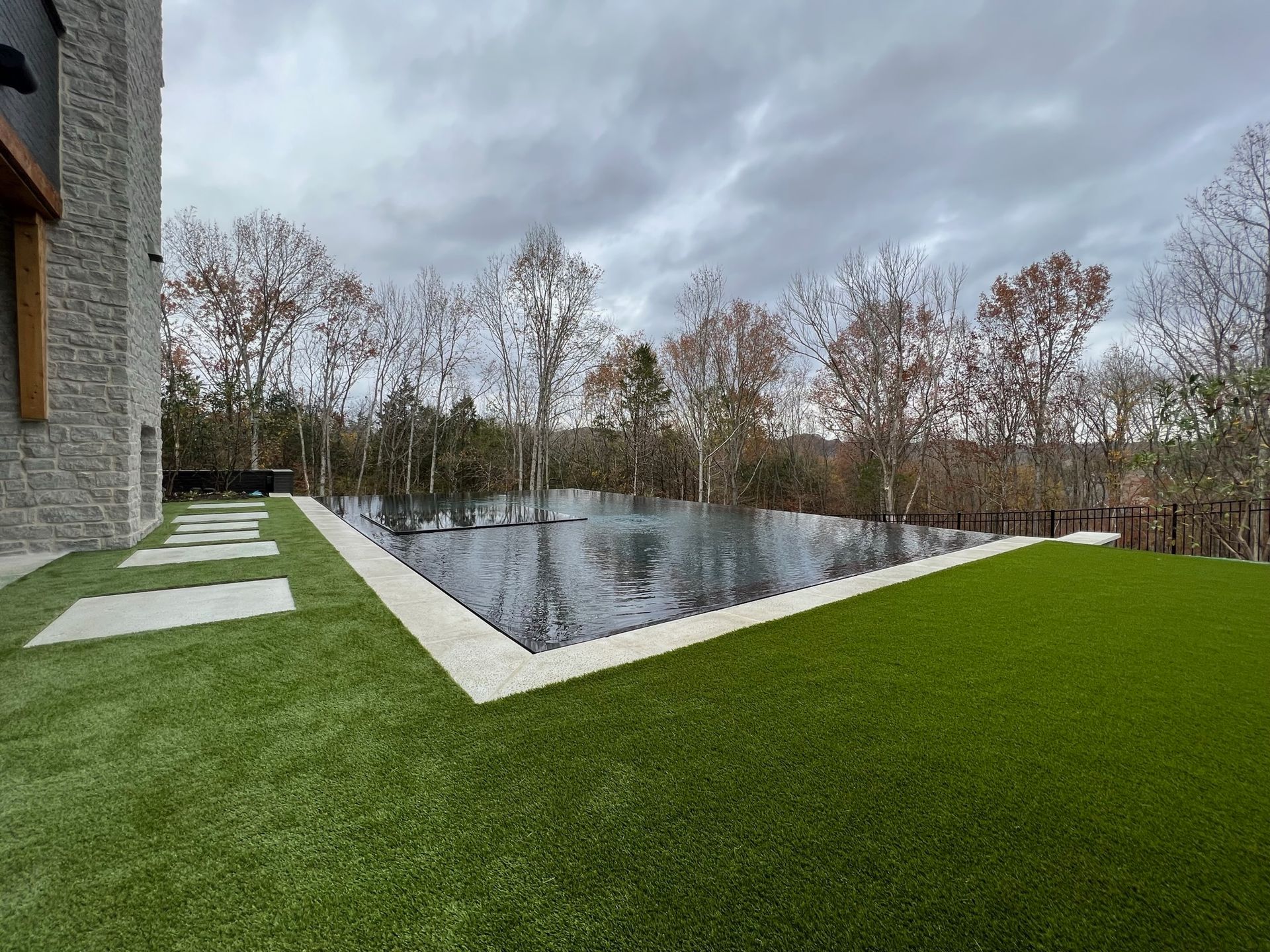 A large swimming pool surrounded by trees and grass in a backyard.