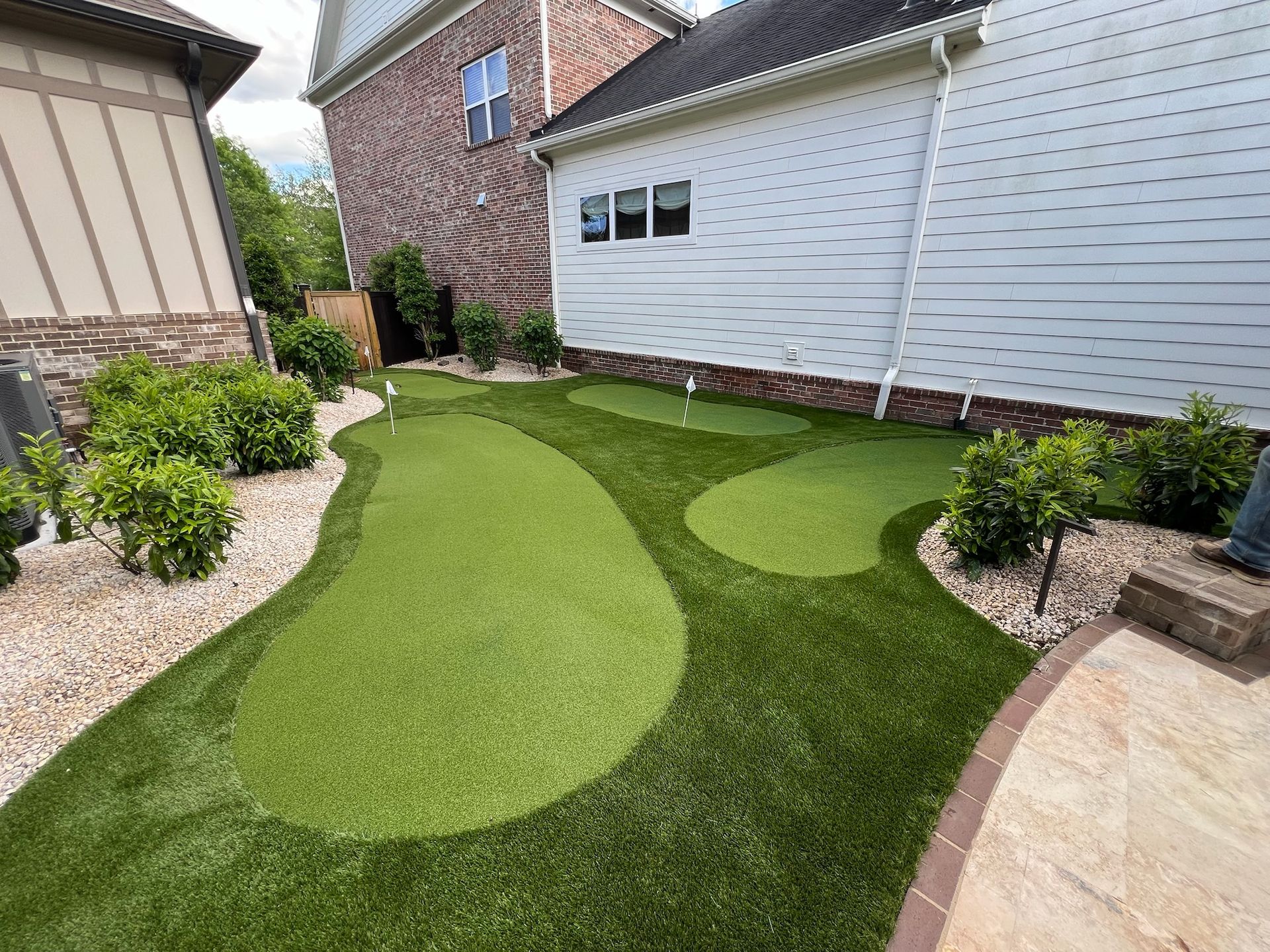 There is a putting green in the backyard of a house.