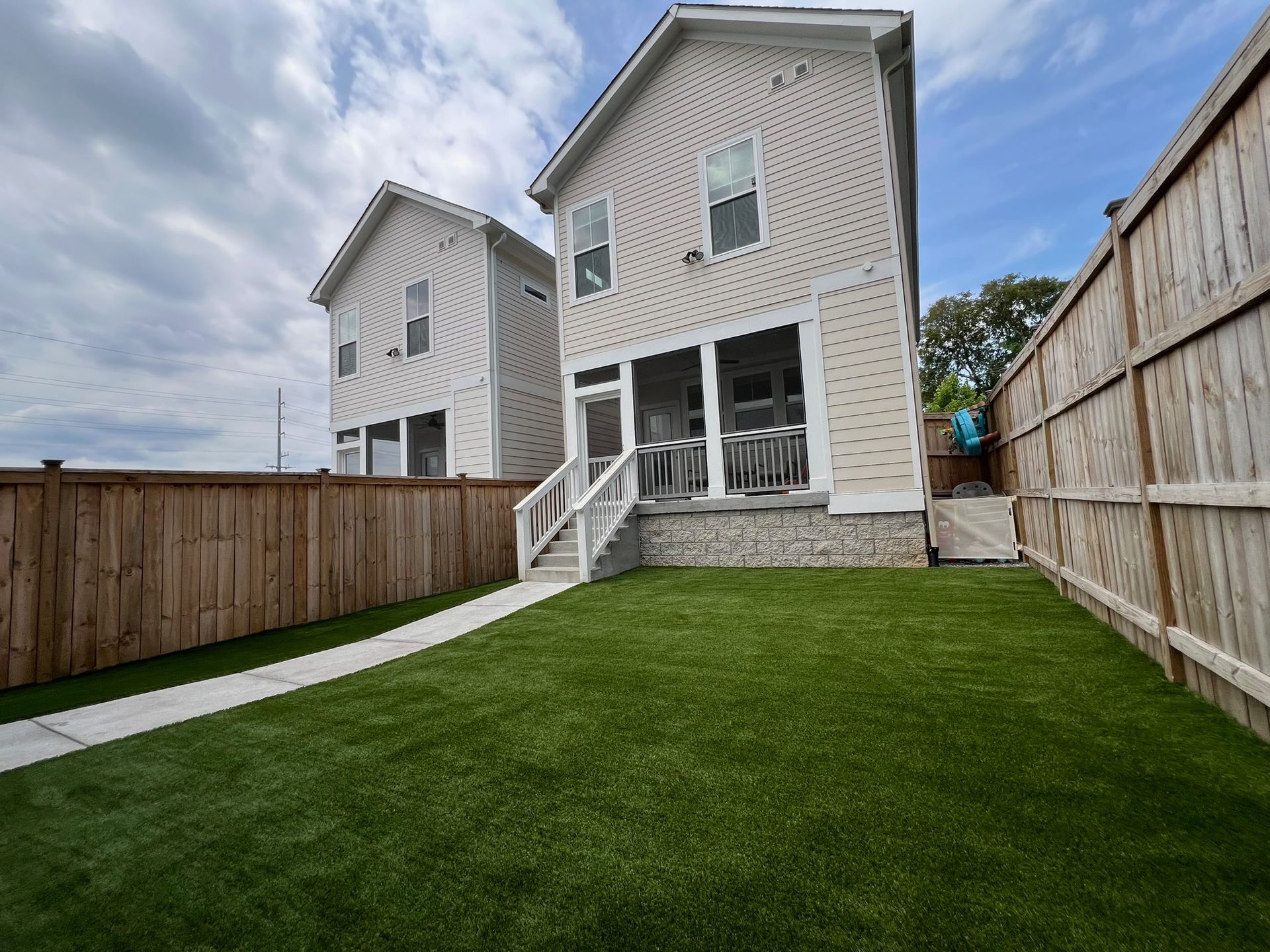 The backyard of a house with a wooden fence and a lush green lawn.