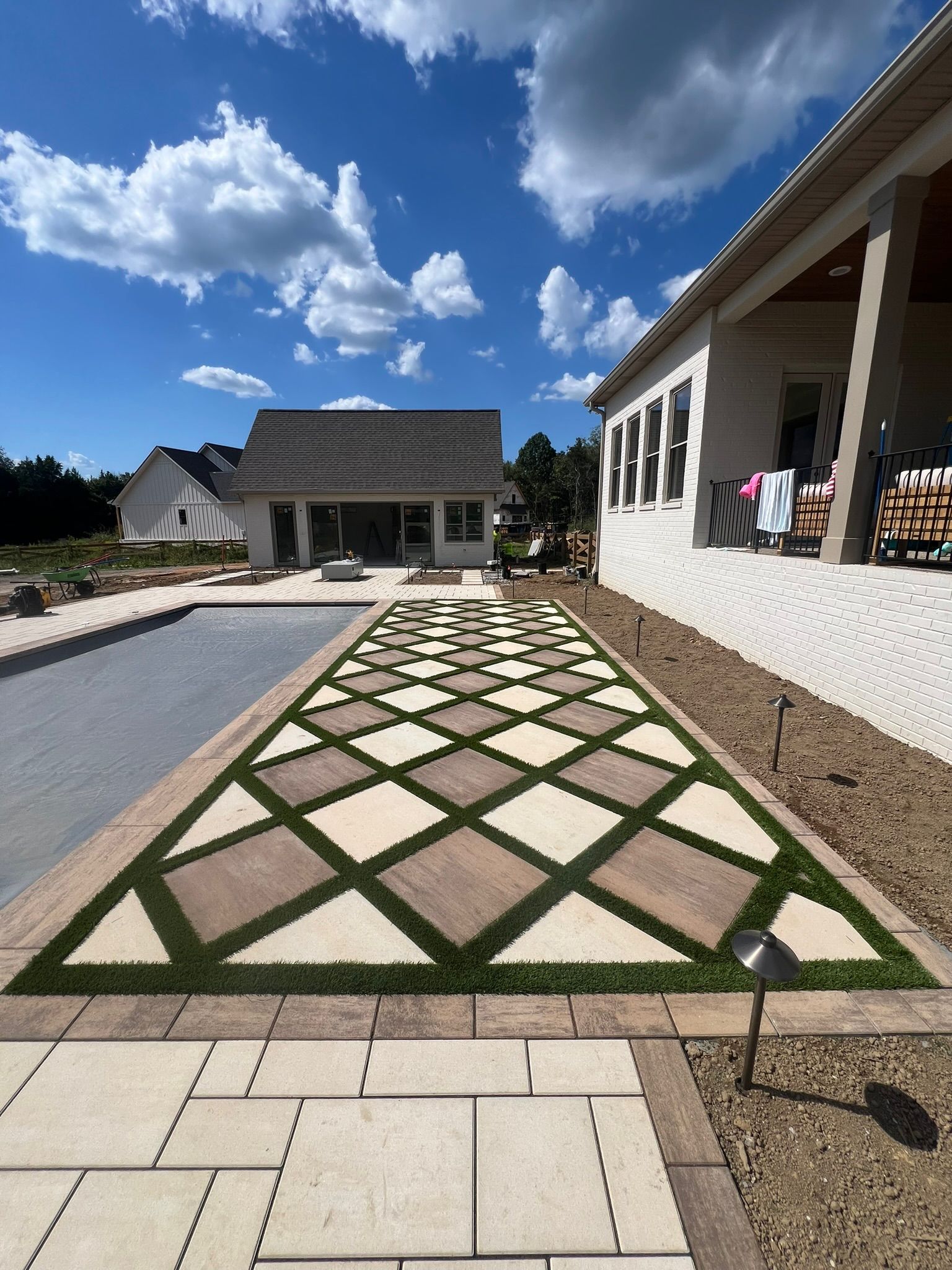 A brick walkway with a geometric pattern on it is leading to a house.