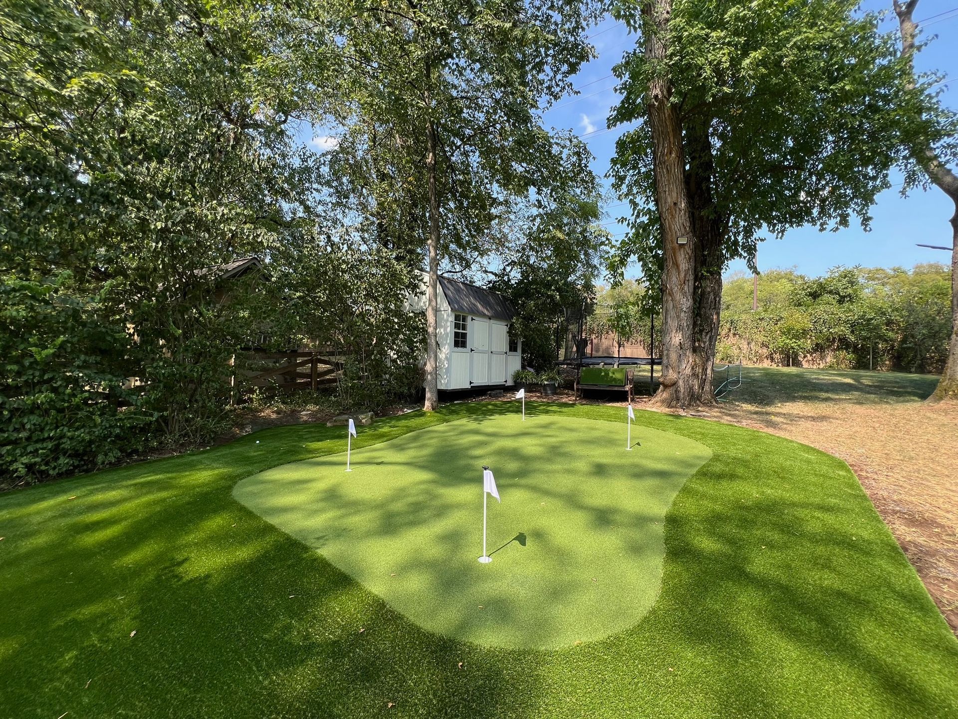 There is a putting green in the backyard of a house.