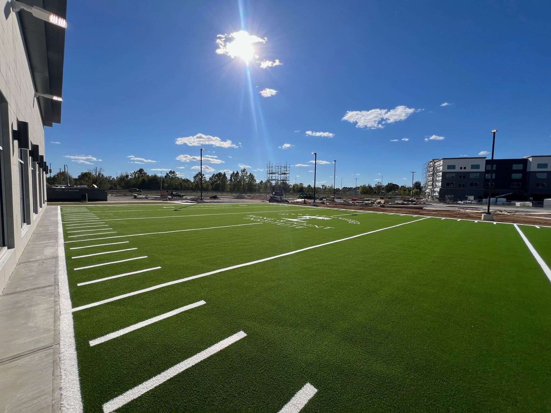A football field is being built in front of a building on a sunny day.