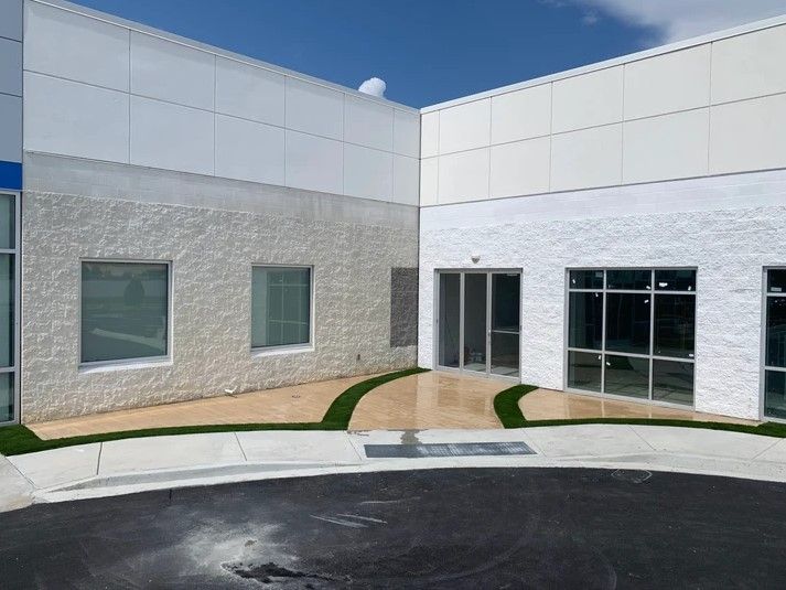 A white building with a lot of windows and a sidewalk in front of it.
