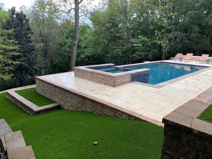 A large swimming pool is surrounded by a lush green lawn.