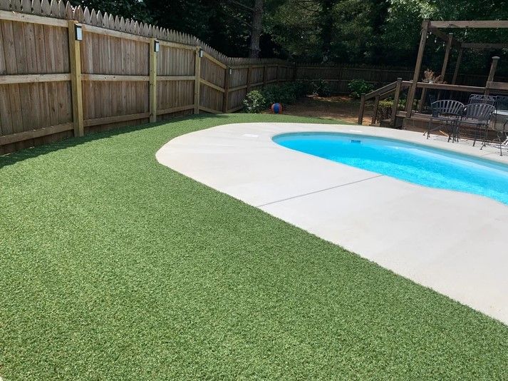 A backyard with a swimming pool and a wooden fence.