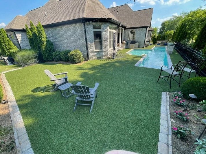 A lawn with chairs and a swimming pool in front of a house.