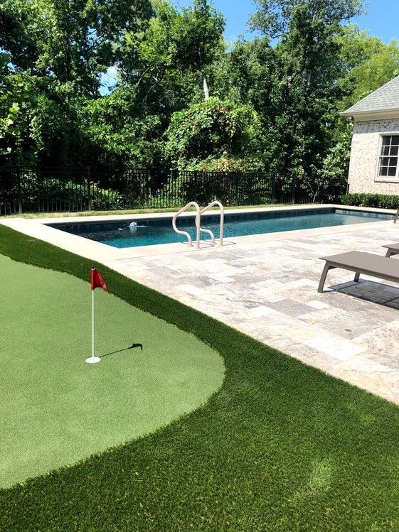 A swimming pool with a putting green in front of it.