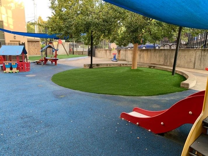 A playground with a red slide and a blue canopy