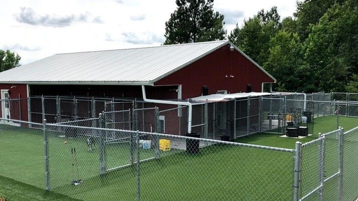 A large red barn with a chain link fence around it.