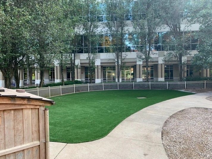 A large building with a lot of windows is behind a lush green field.