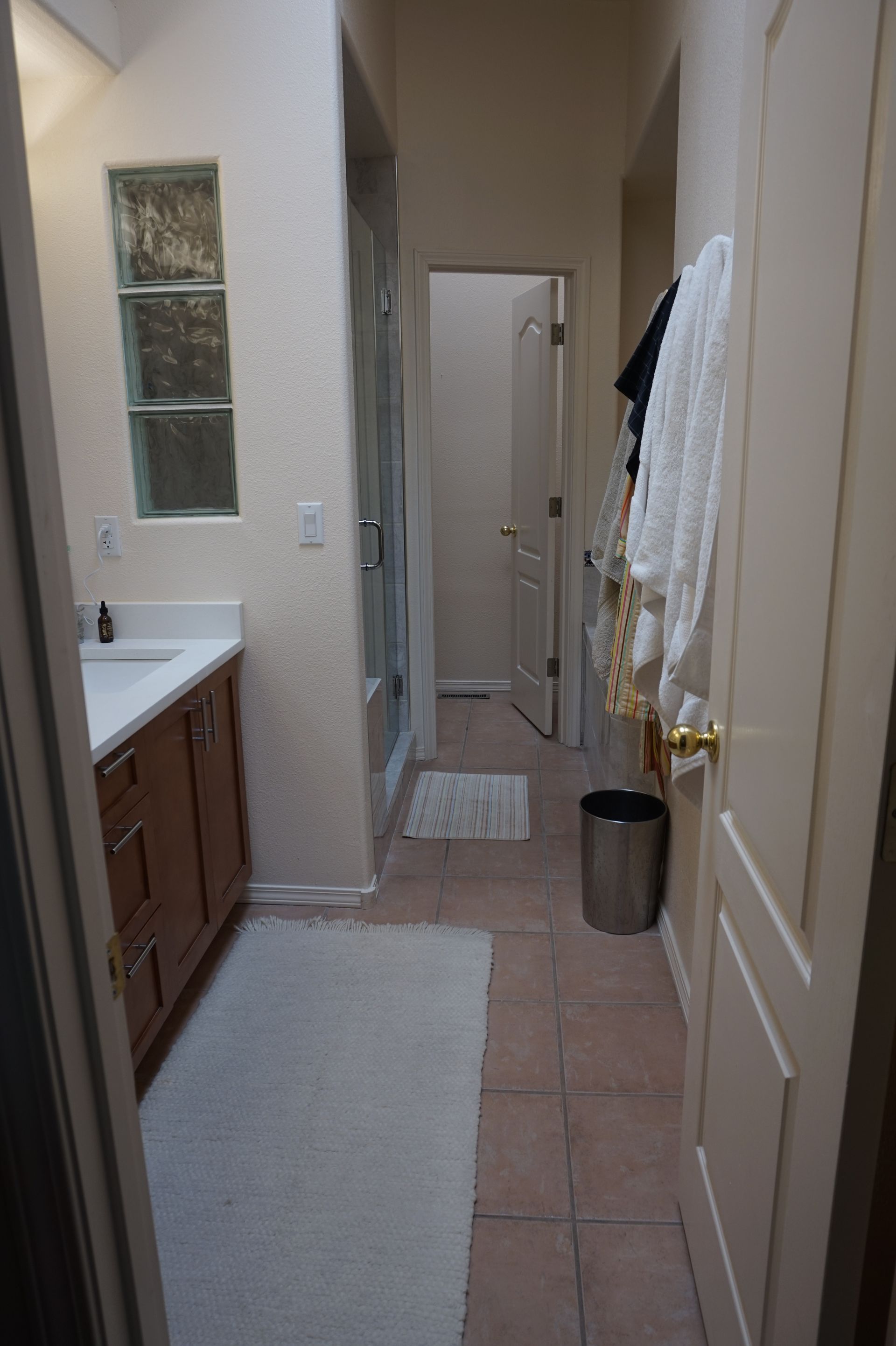 a bathroom with a sink, cabinets, and a trash can