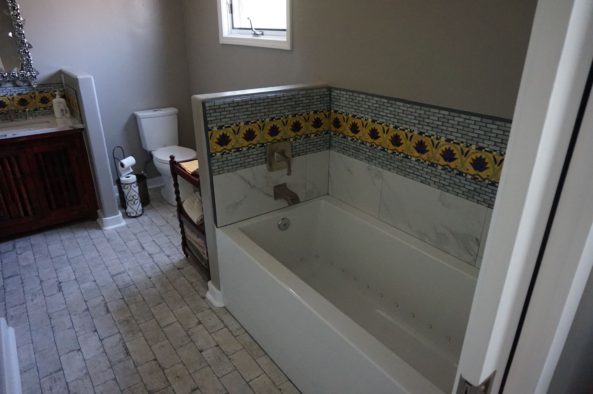 a bathroom with a tub, toilet, sink and mirror