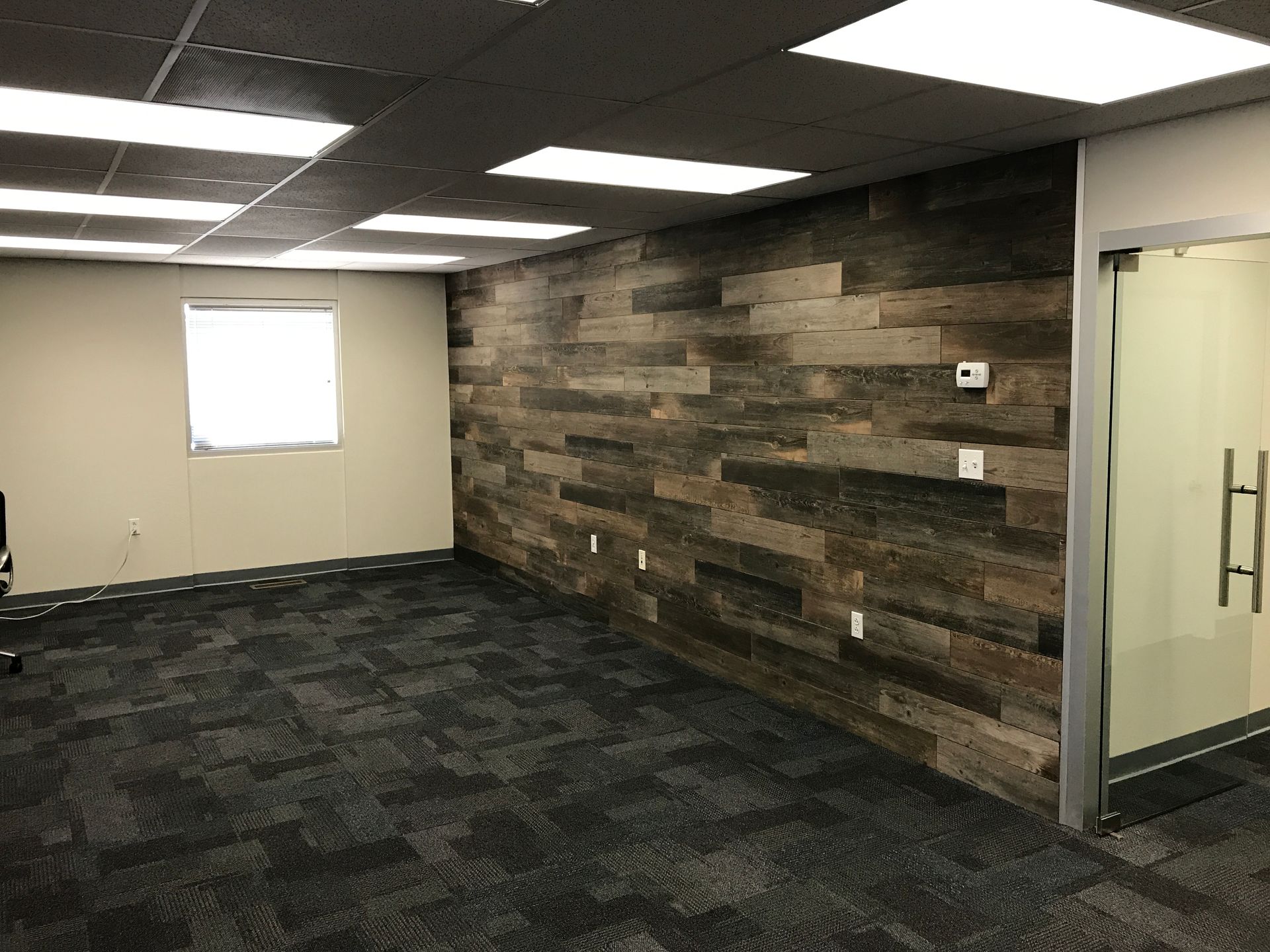 an empty room with a wooden wall and a glass door