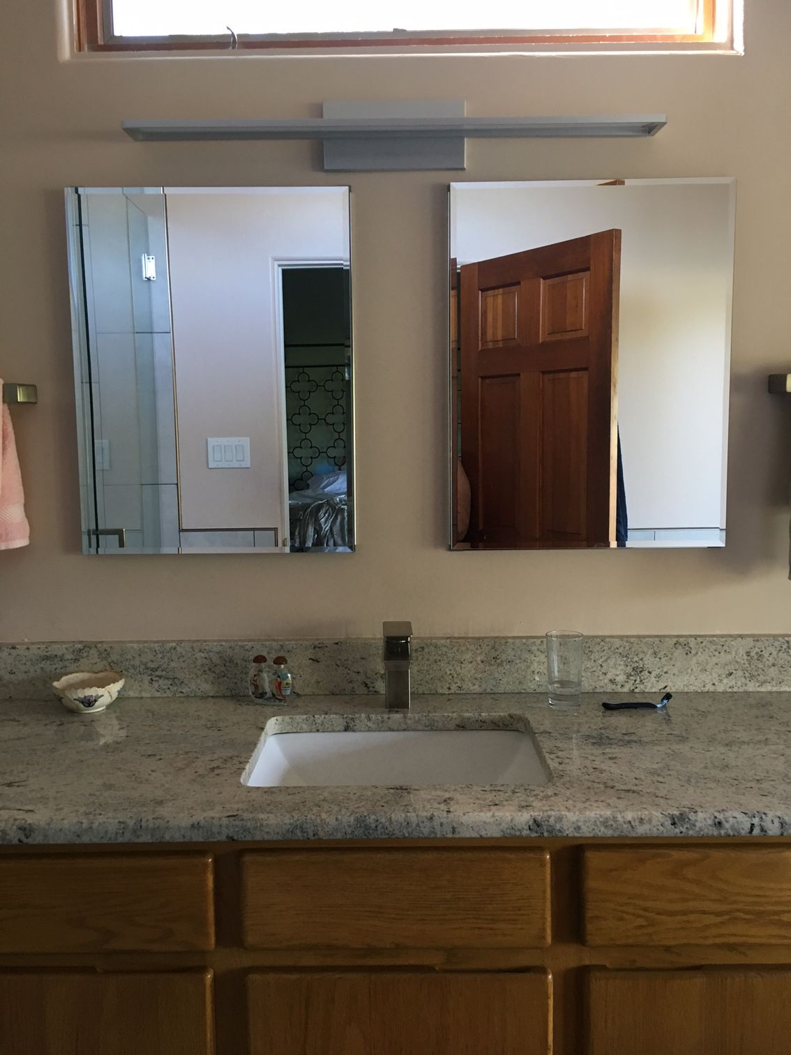 a bathroom with a sink and two mirrors above it