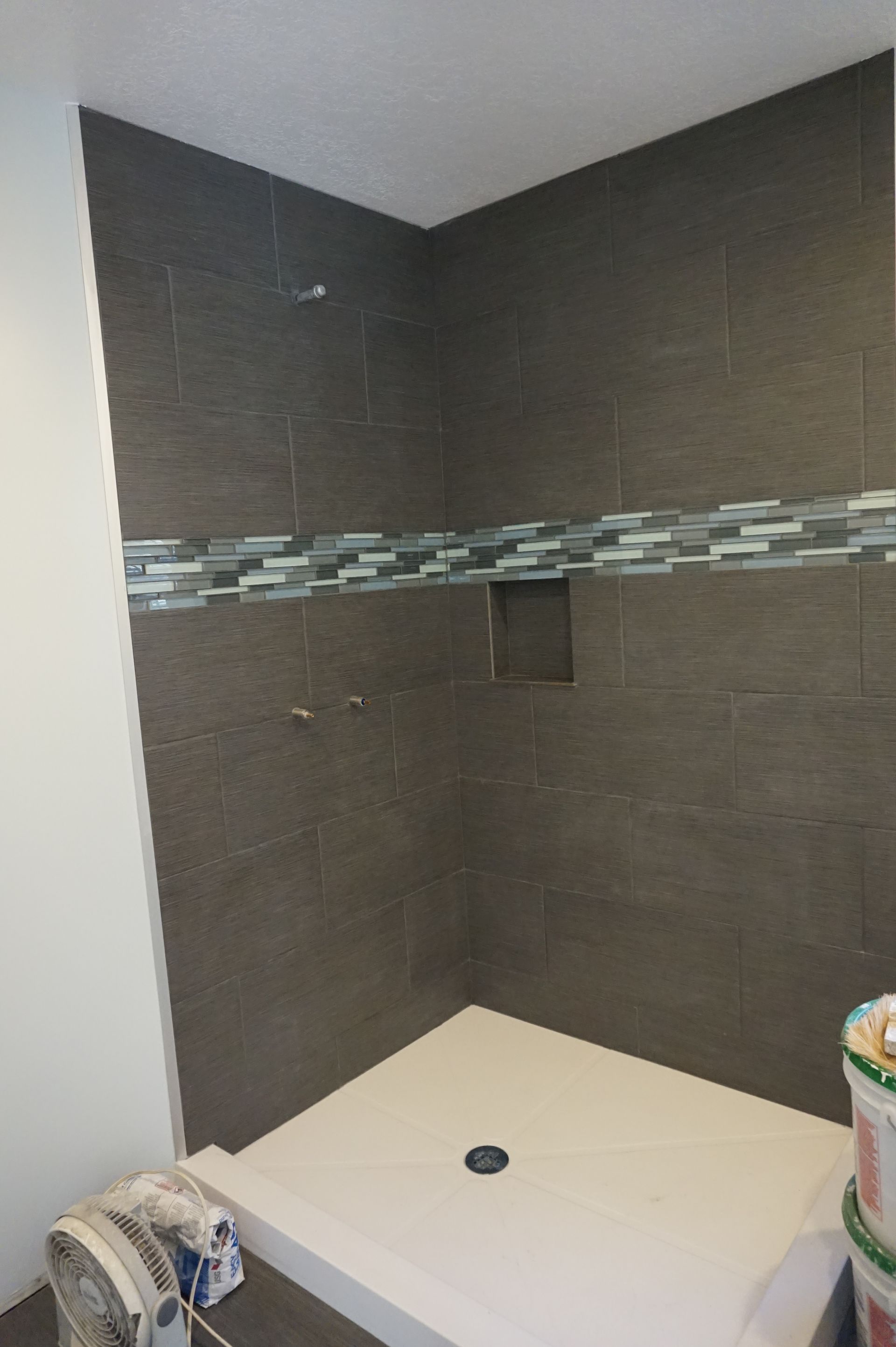 a bathroom with a walk in shower and a fan