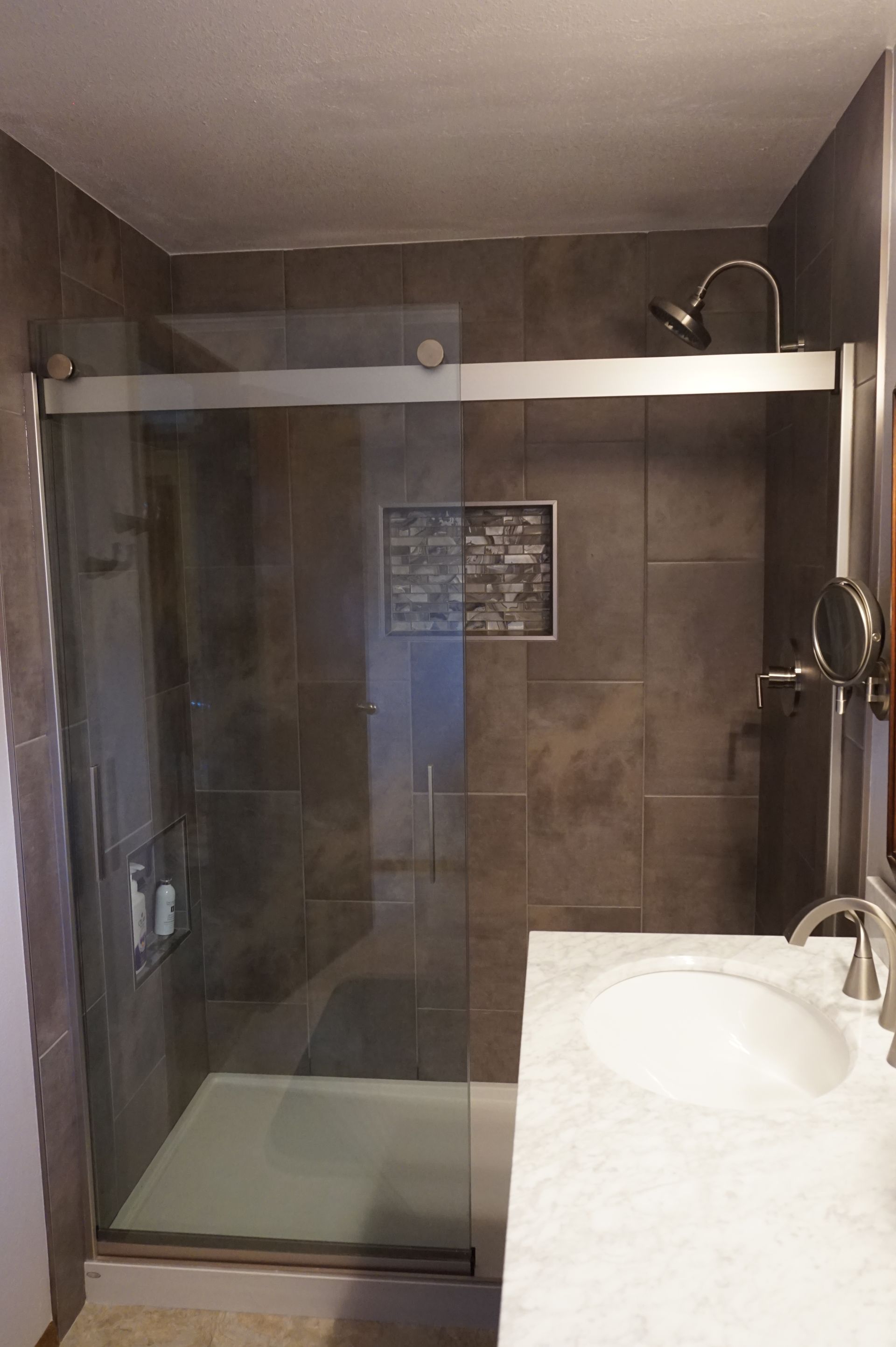a bathroom with a sliding glass shower door and a sink
