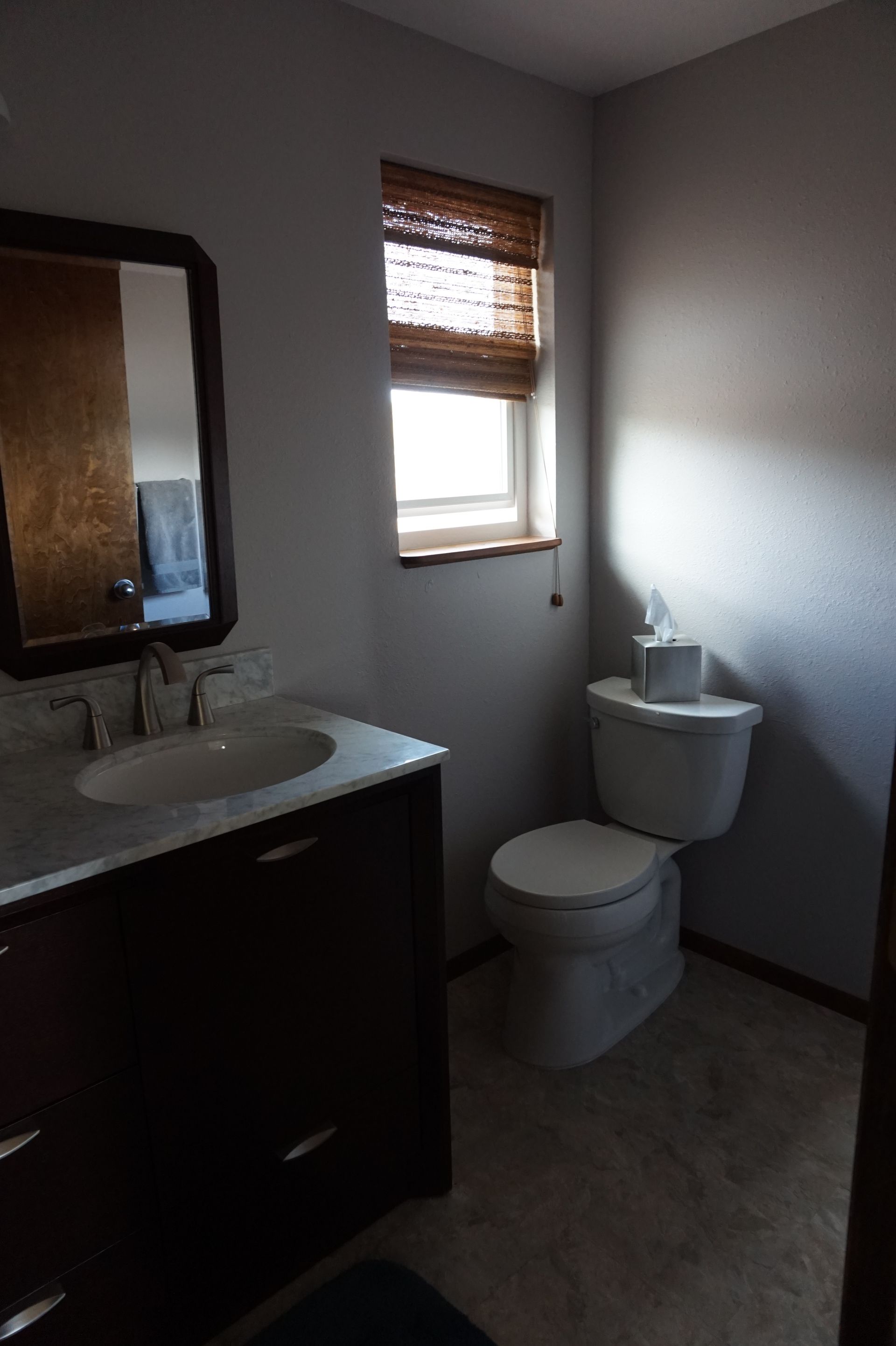 a bathroom with a toilet, sink, mirror and window
