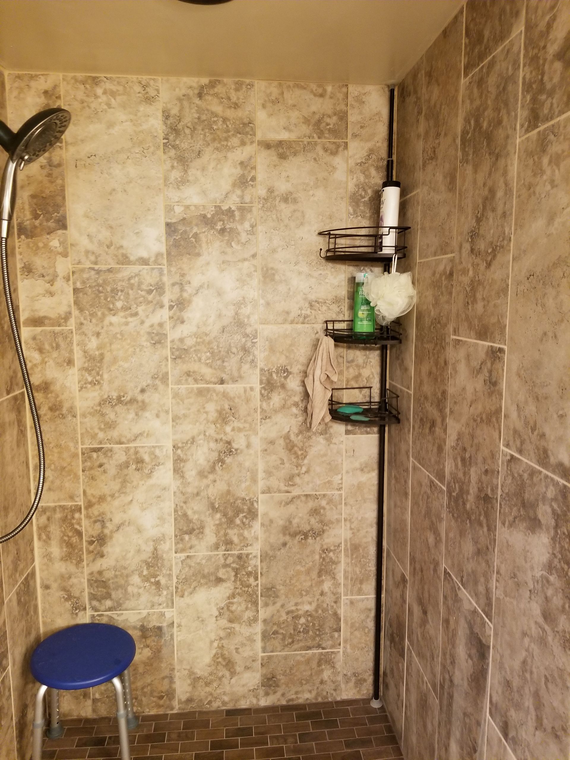 a shower with a blue stool and a shower head