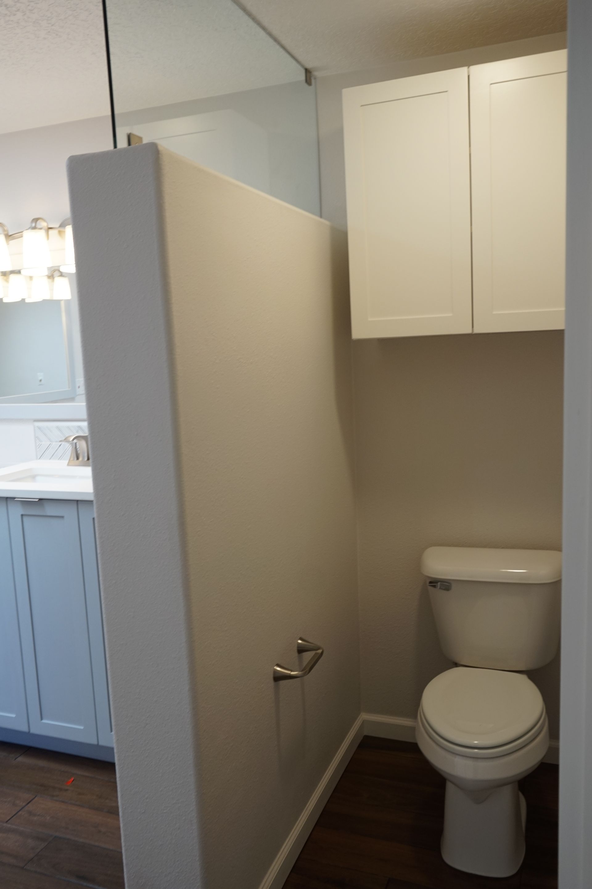 a bathroom with a toilet, sink and cabinets