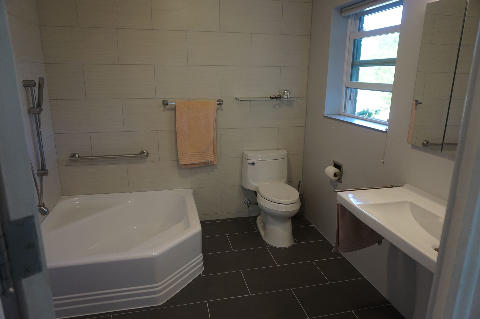 a bathroom with a tub, toilet, sink and mirror