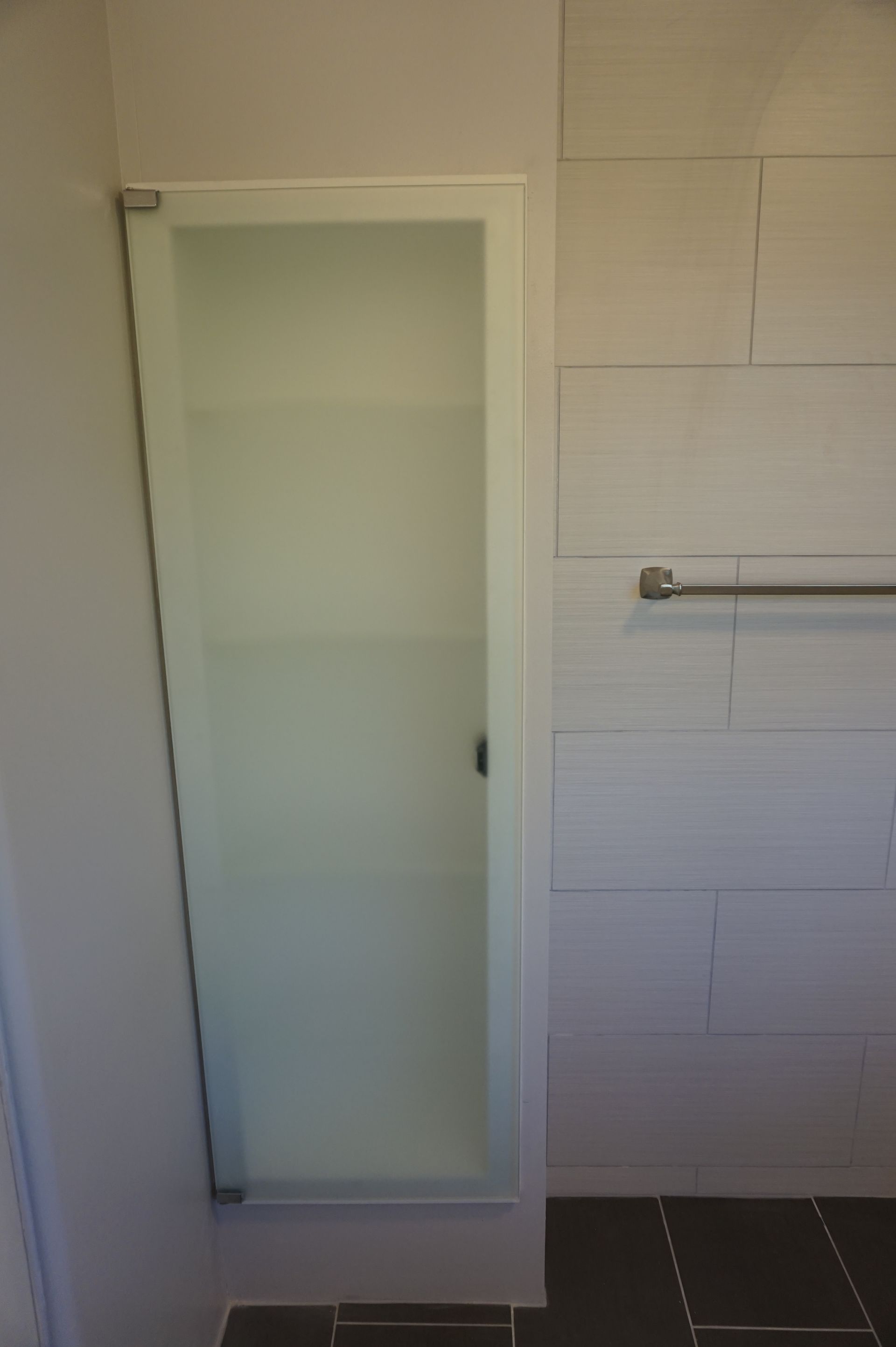 a bathroom with a glass shower door and a towel rack
