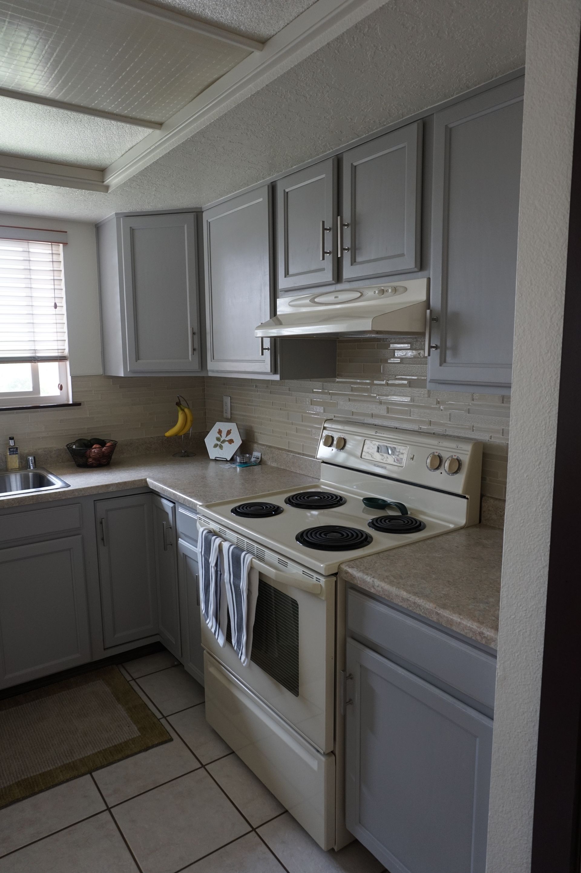 a kitchen with gray cabinets and a white stove top oven