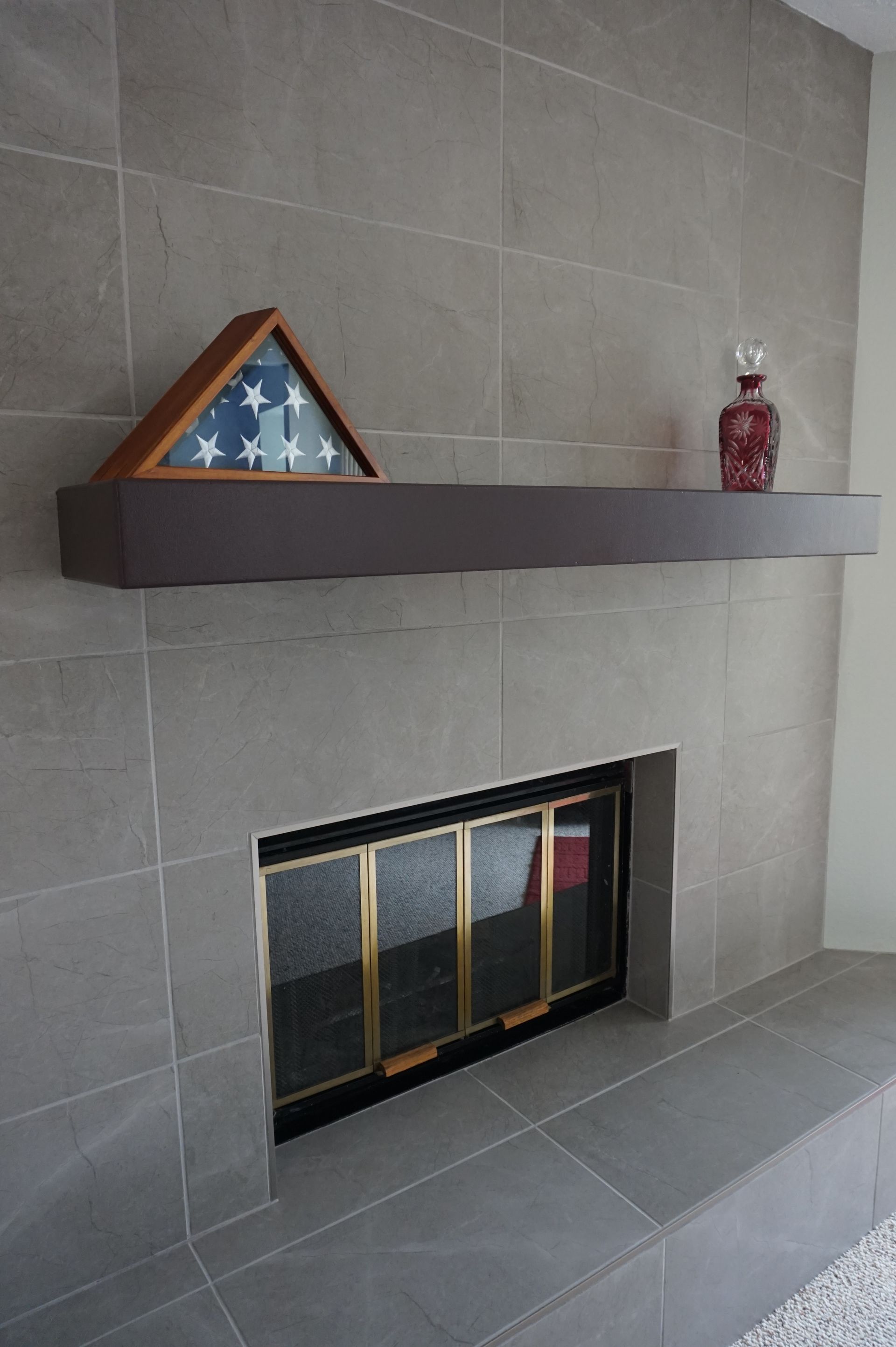 a fireplace with a flag on the mantle and a vase on the shelf