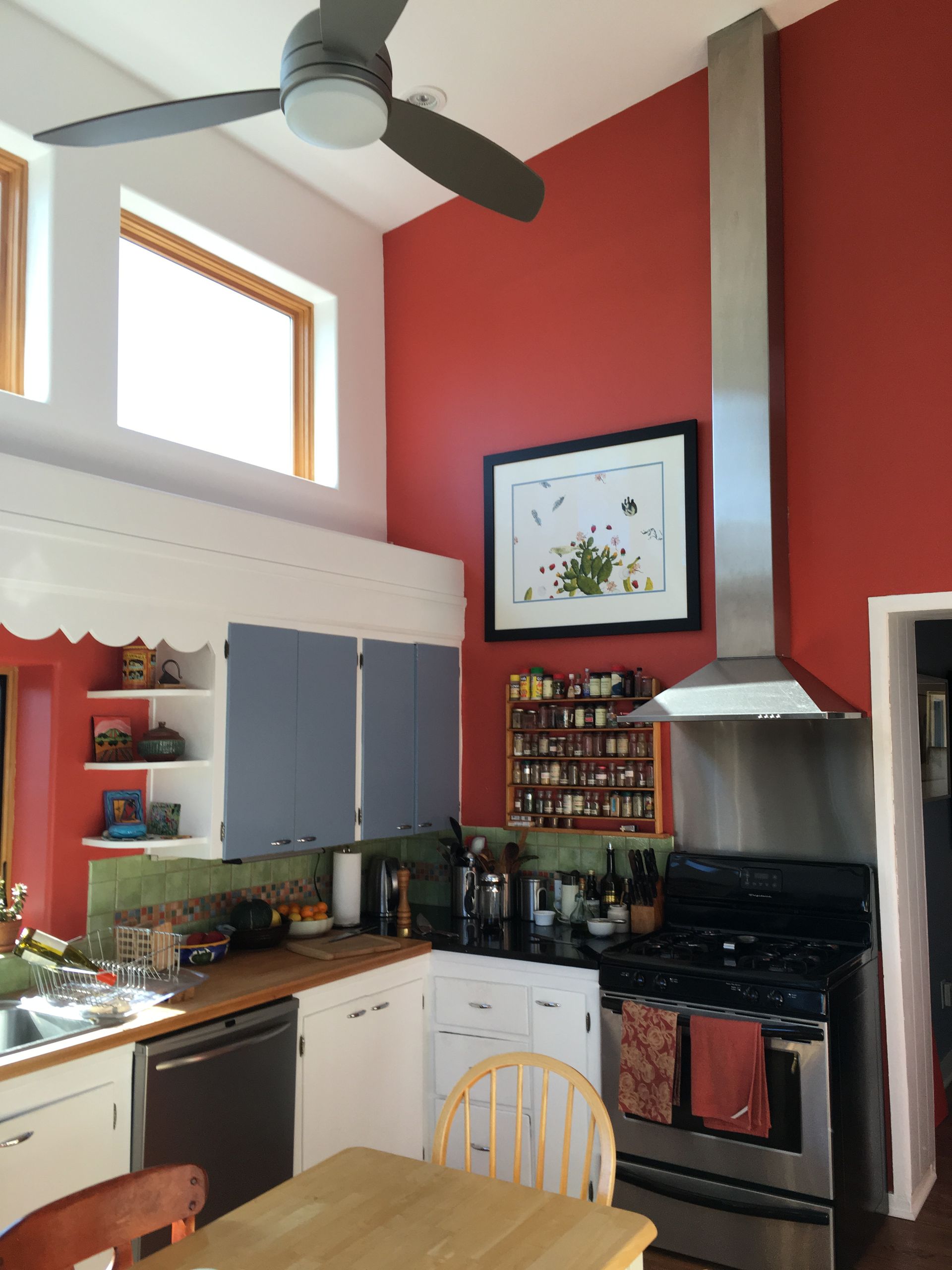 a kitchen with red walls and a ceiling fan