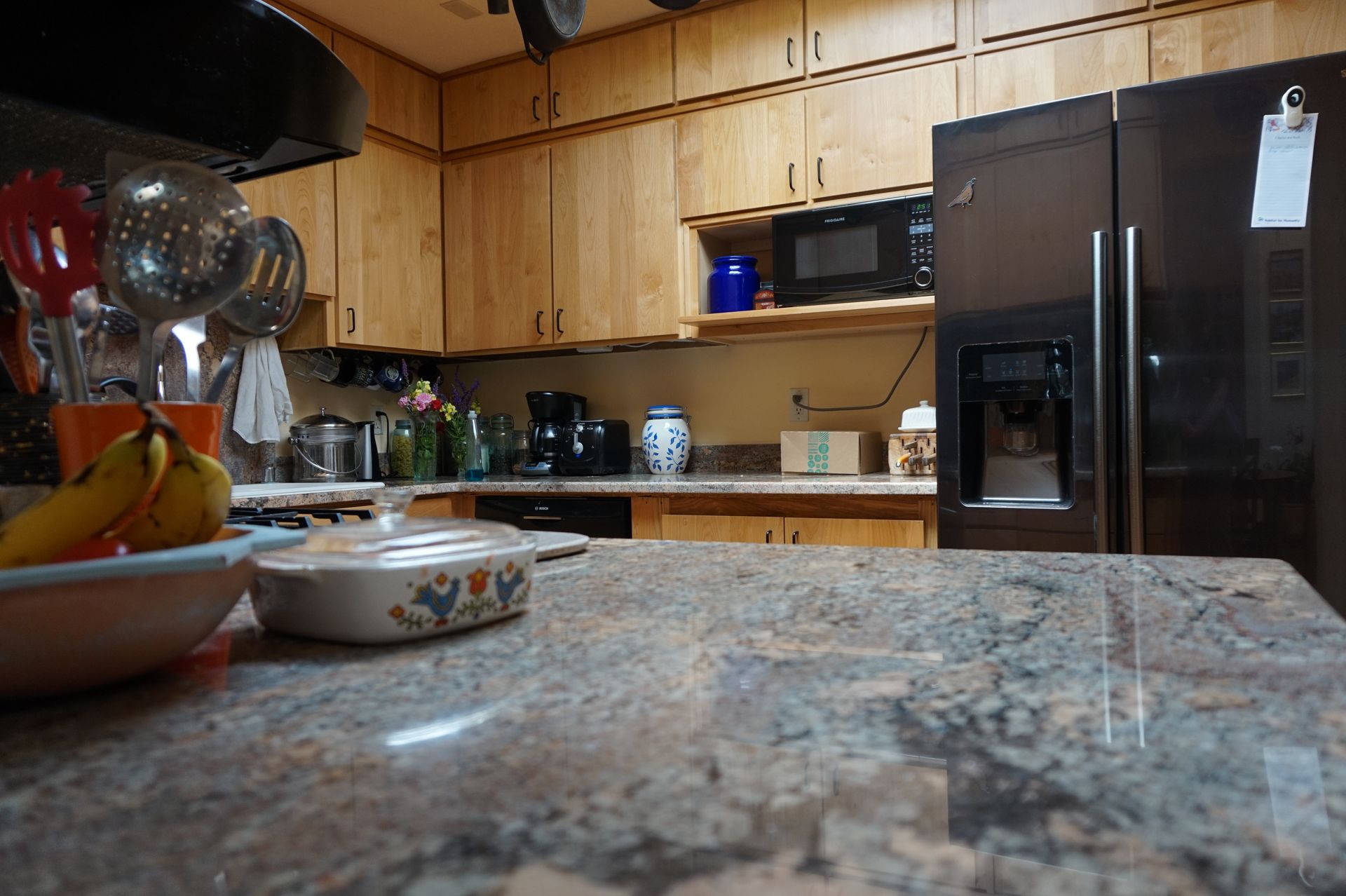 a kitchen with a refrigerator and a bowl of bananas on the counter