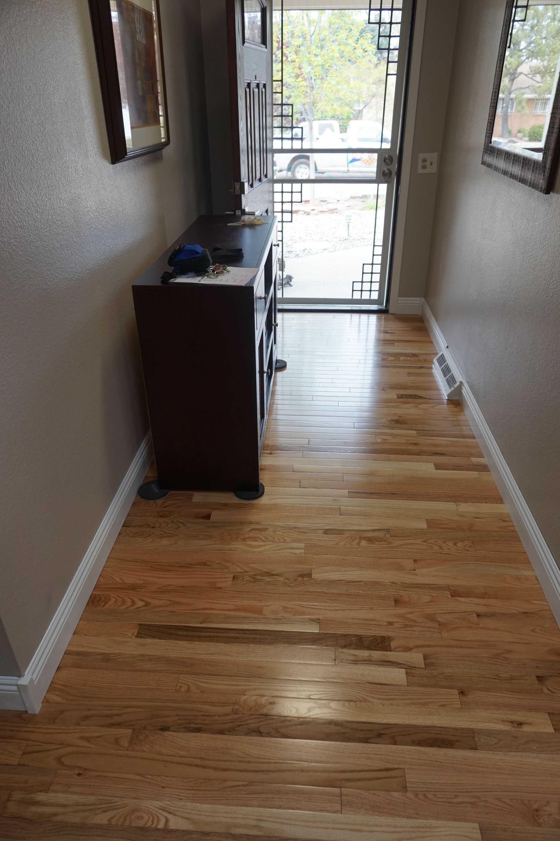 a hallway with hardwood floors and a dresser in the middle