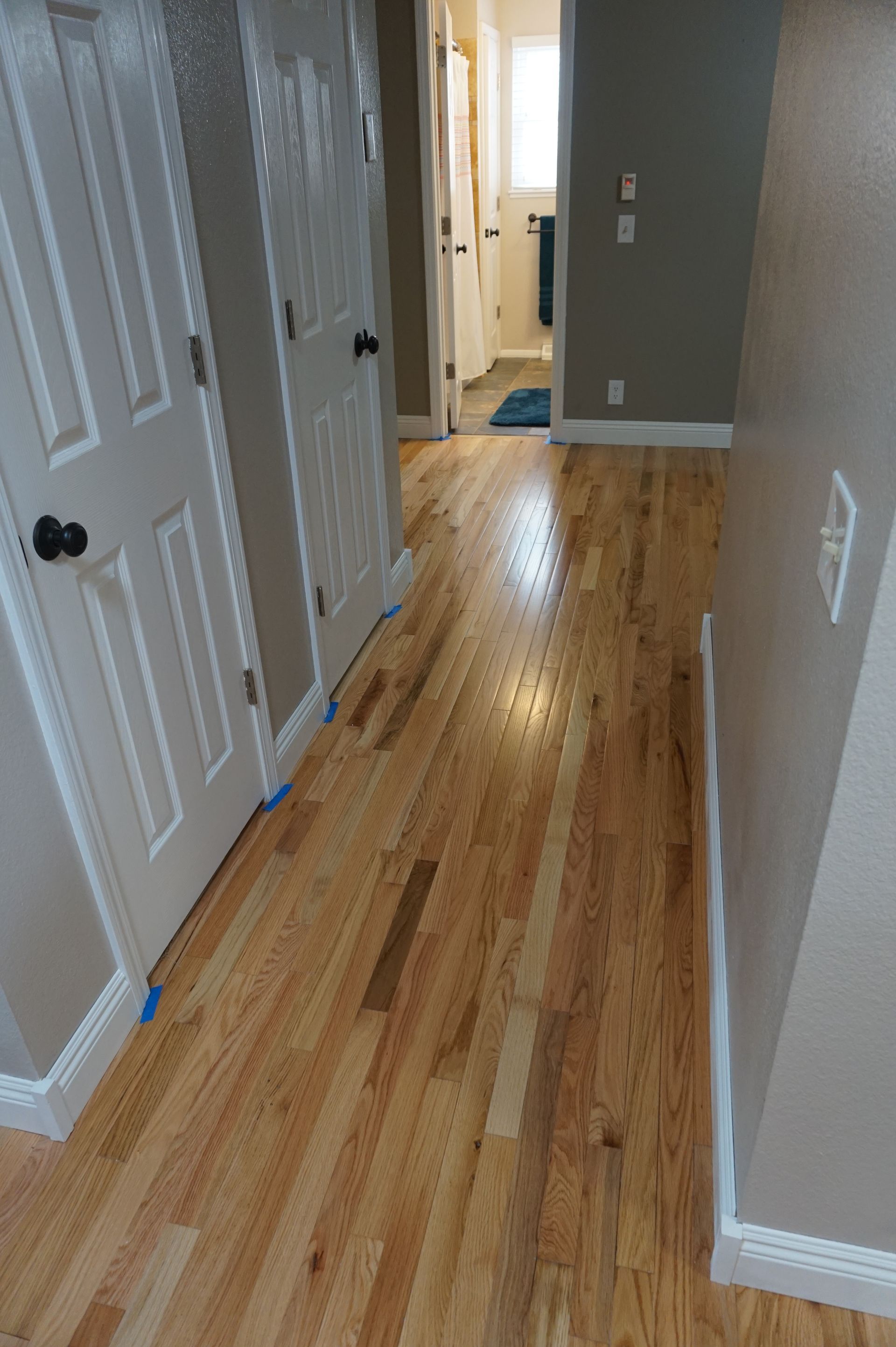 a hallway with hardwood floors and white doors in a house