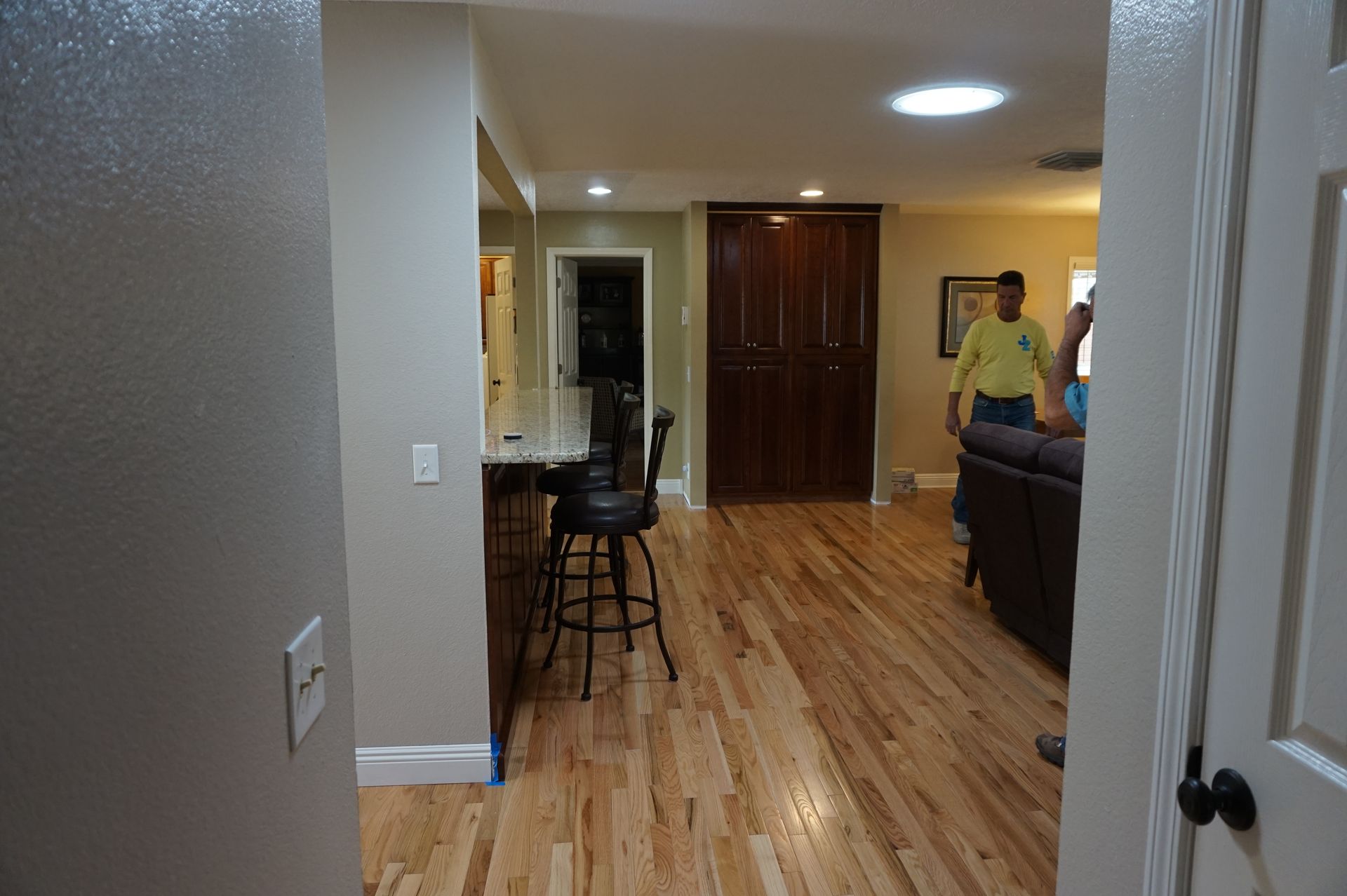 a man in a yellow shirt is standing in a living room with hardwood floors
