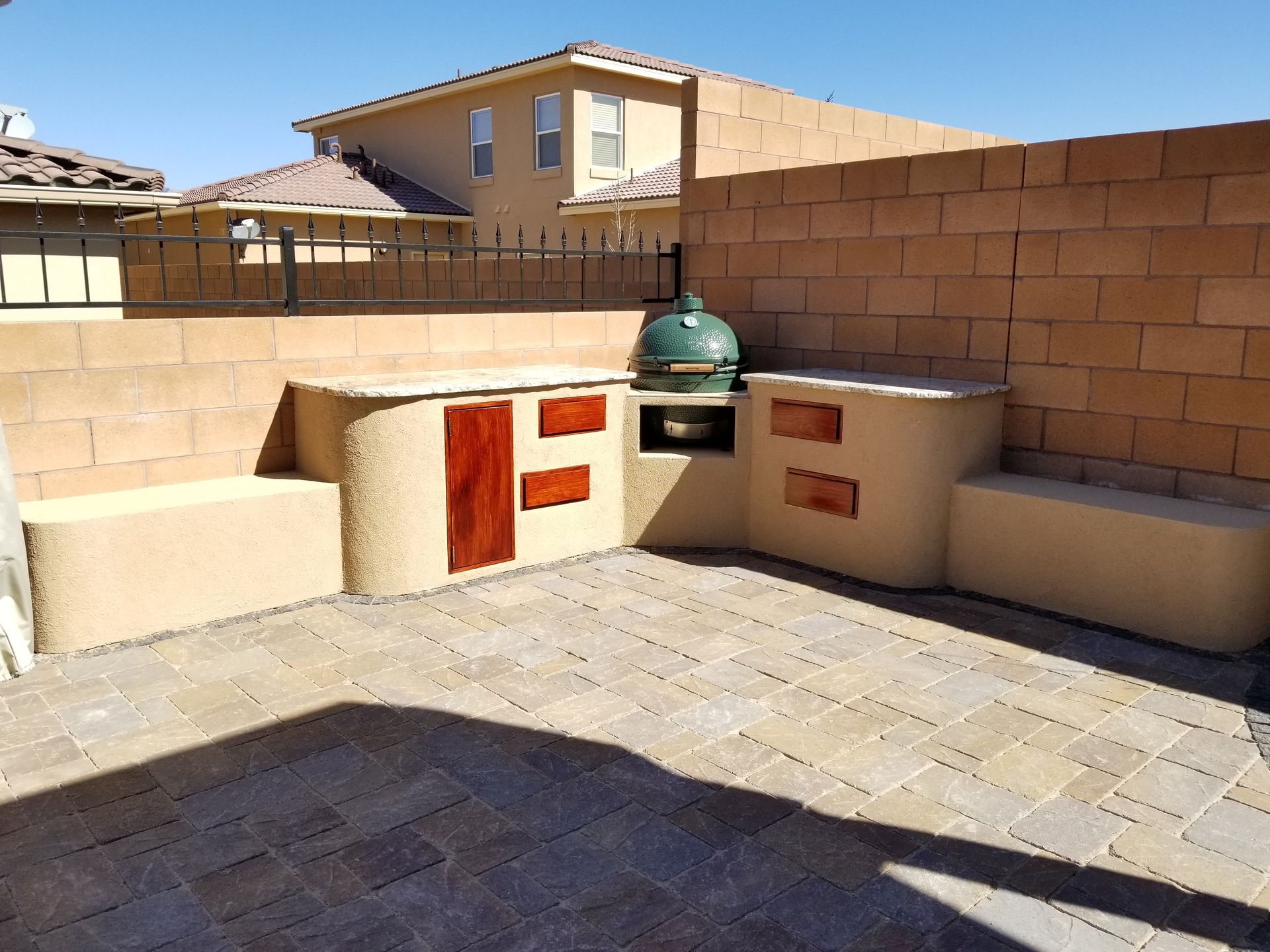a patio with a brick wall and a green grill cover