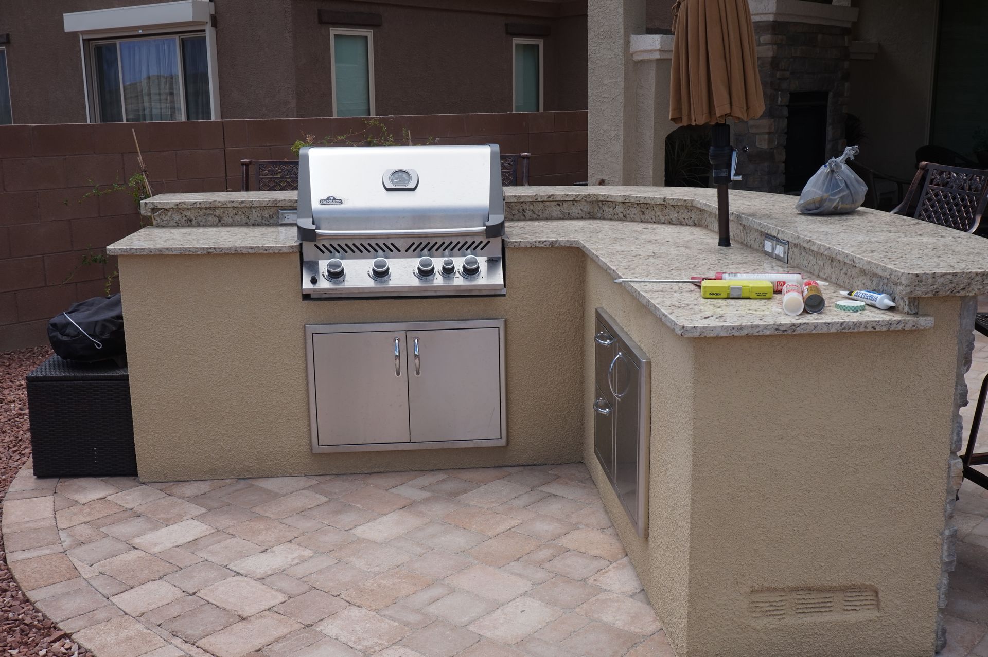 an outdoor kitchen with a stainless steel grill and granite counter tops