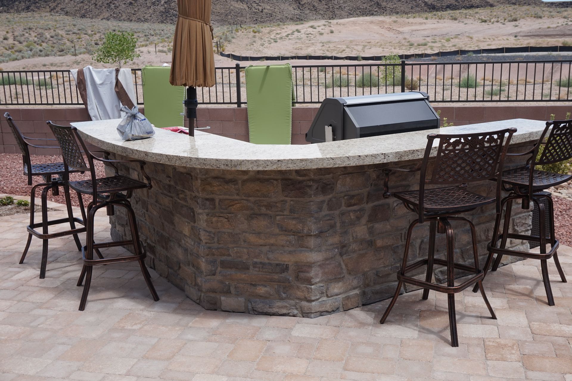 a brick bar with chairs and umbrellas on a patio