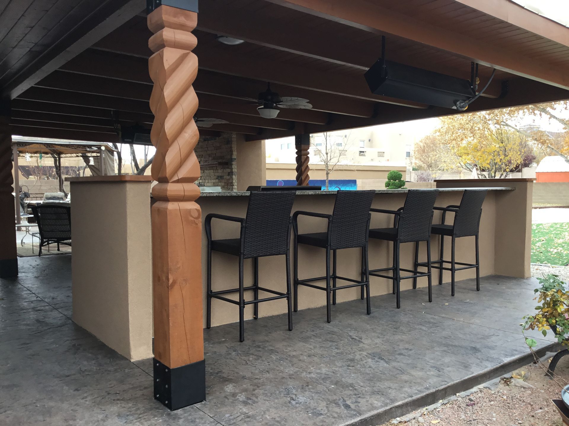 a patio with a bar and chairs under a pergola