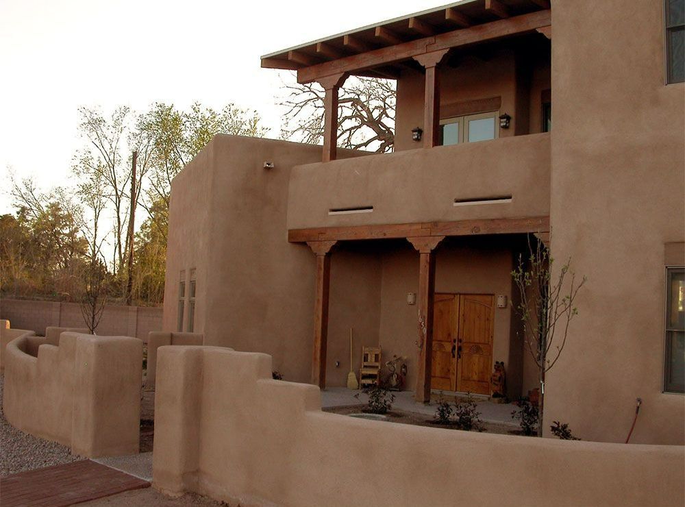 a large adobe building with a porch and a wooden door
