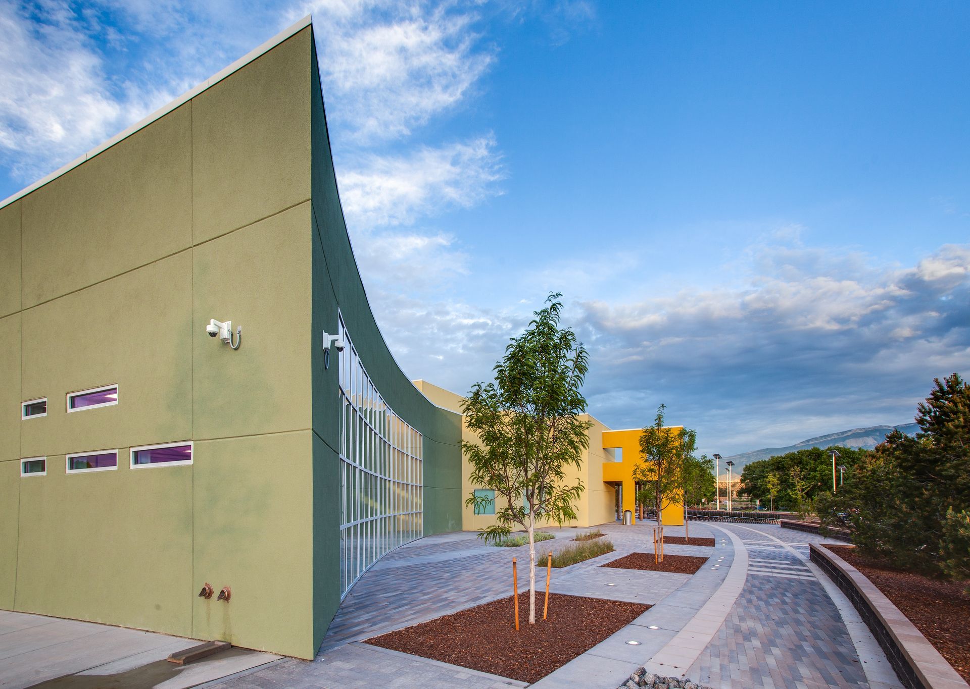 a green building with a lot of windows and trees in front of it