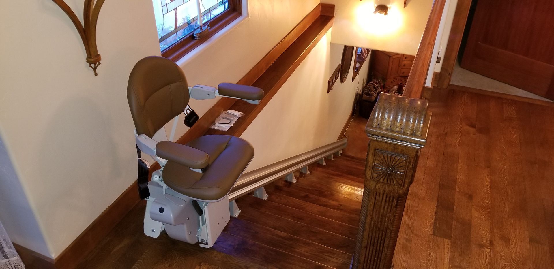 A stair lift is sitting on the bottom of a wooden staircase