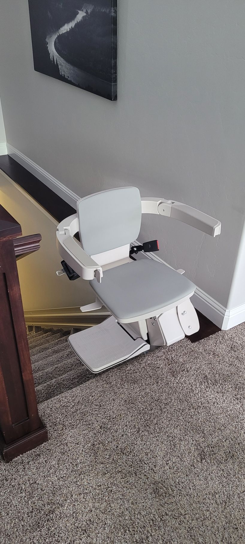 A white stair lift is sitting on a carpeted floor in a living room
