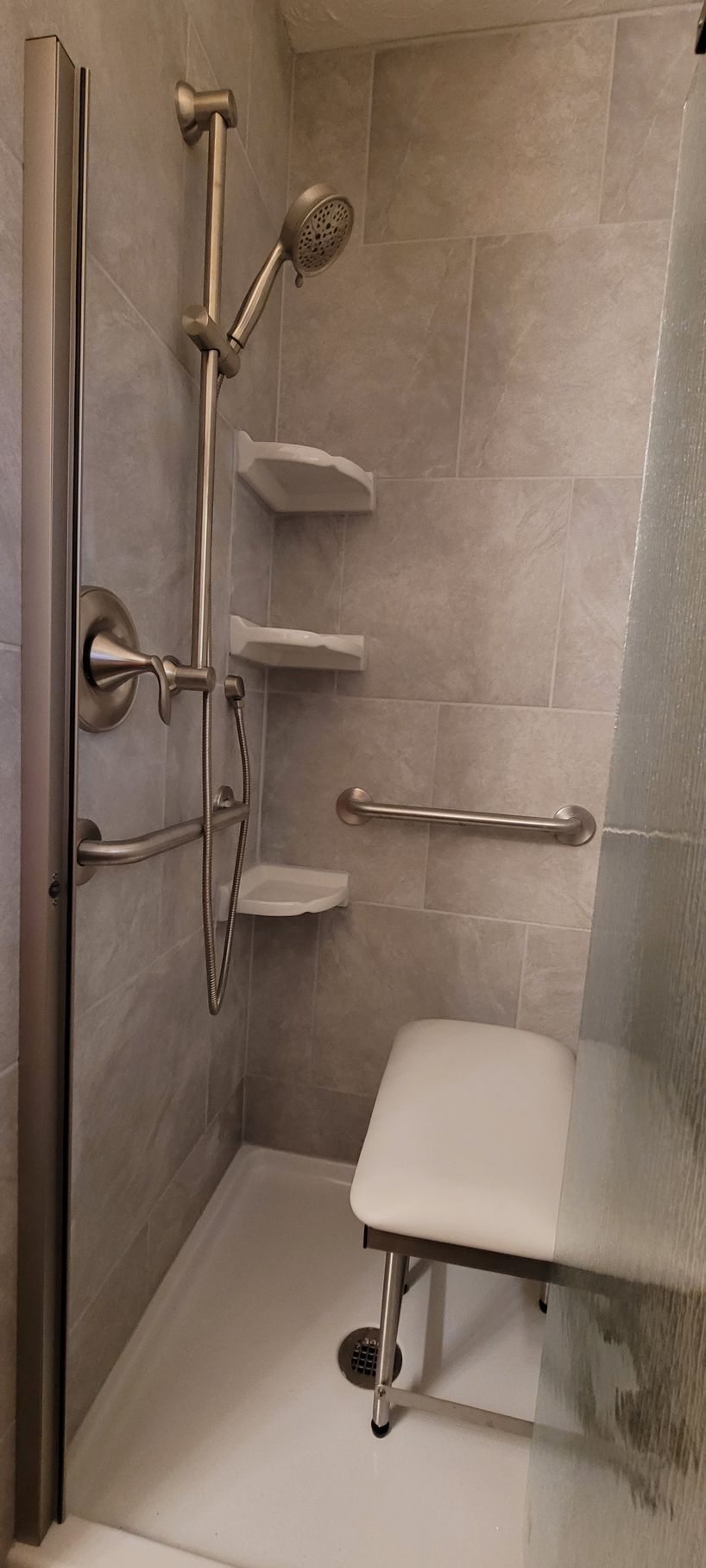 A shower with a seat and a shower head