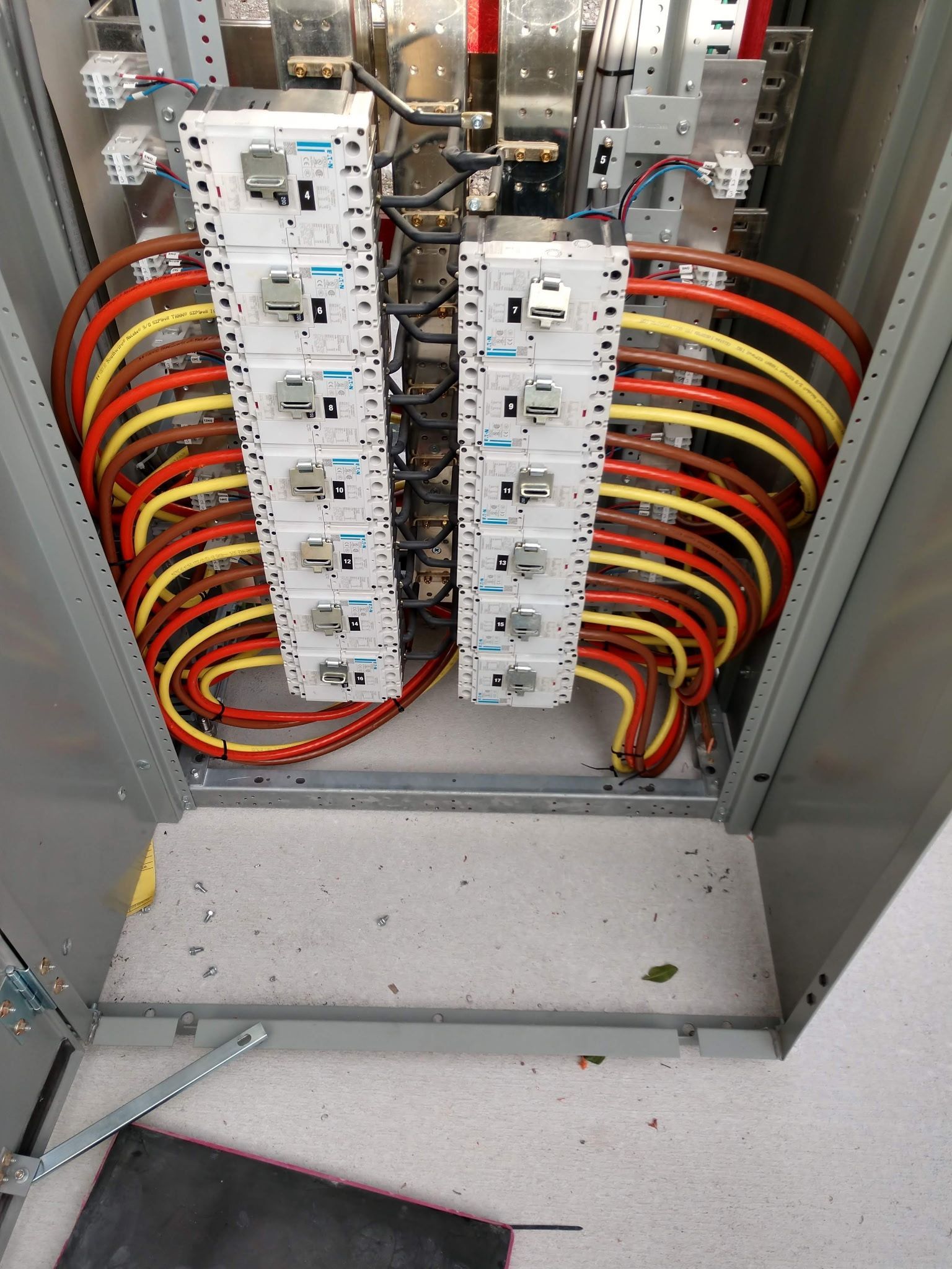 Electrical panel with rows of circuit breakers and colored wires.