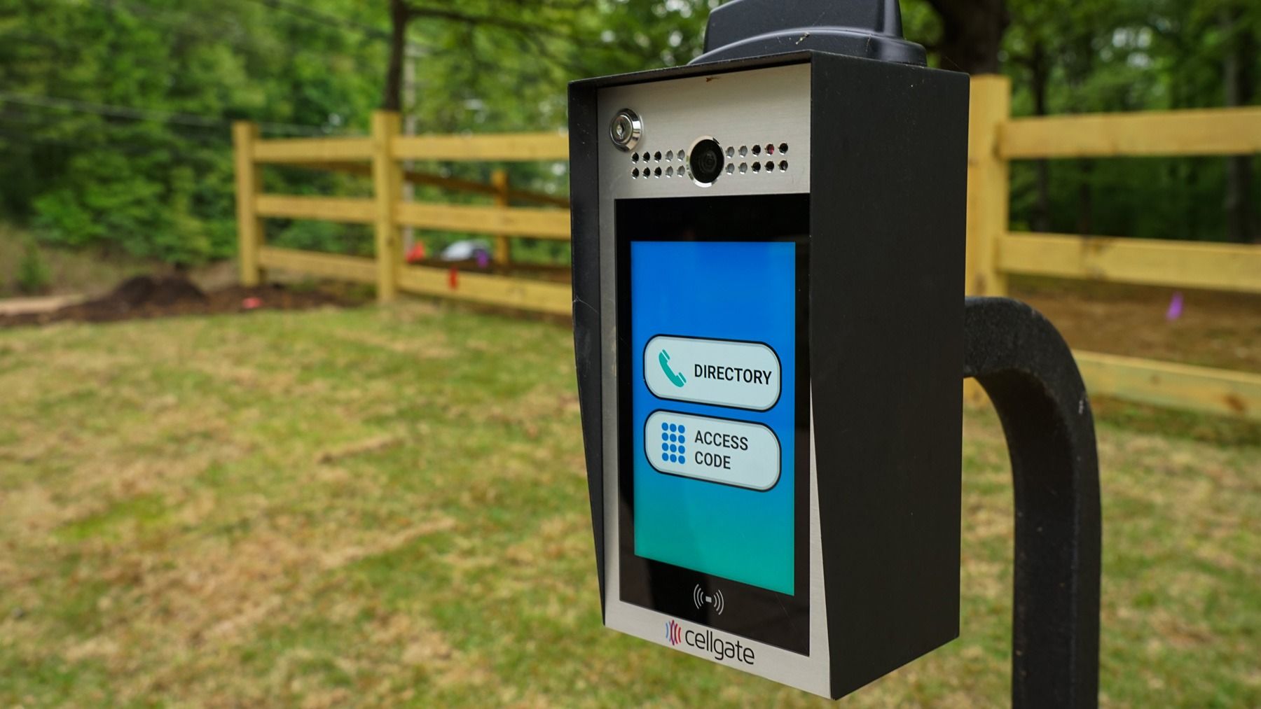 A cell phone sitting on top of a pole next to a fence.