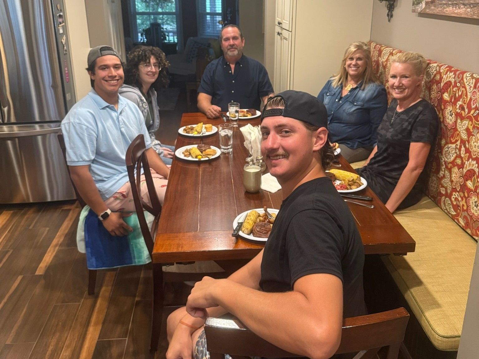 Group seated around a long dining table, smiling at a restaurant meal.