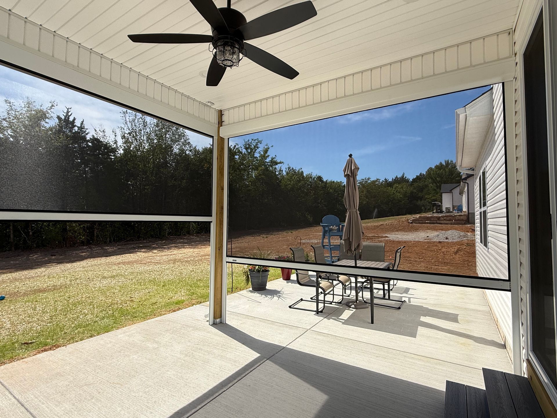 Covered patio with screens and a view of a backyard with outdoor furniture.
