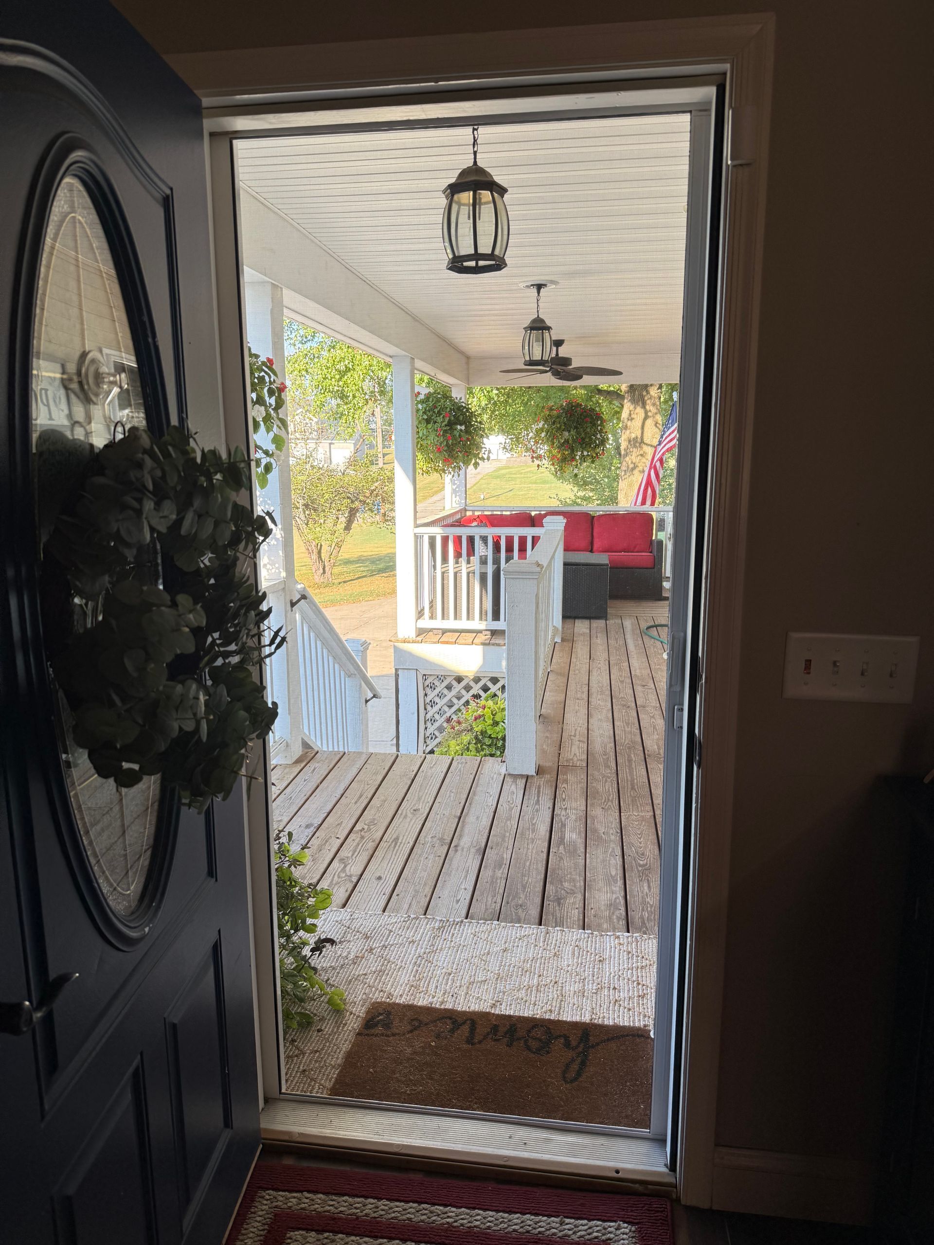Open doorway reveals a front porch with seating, hanging plants, and lanterns.