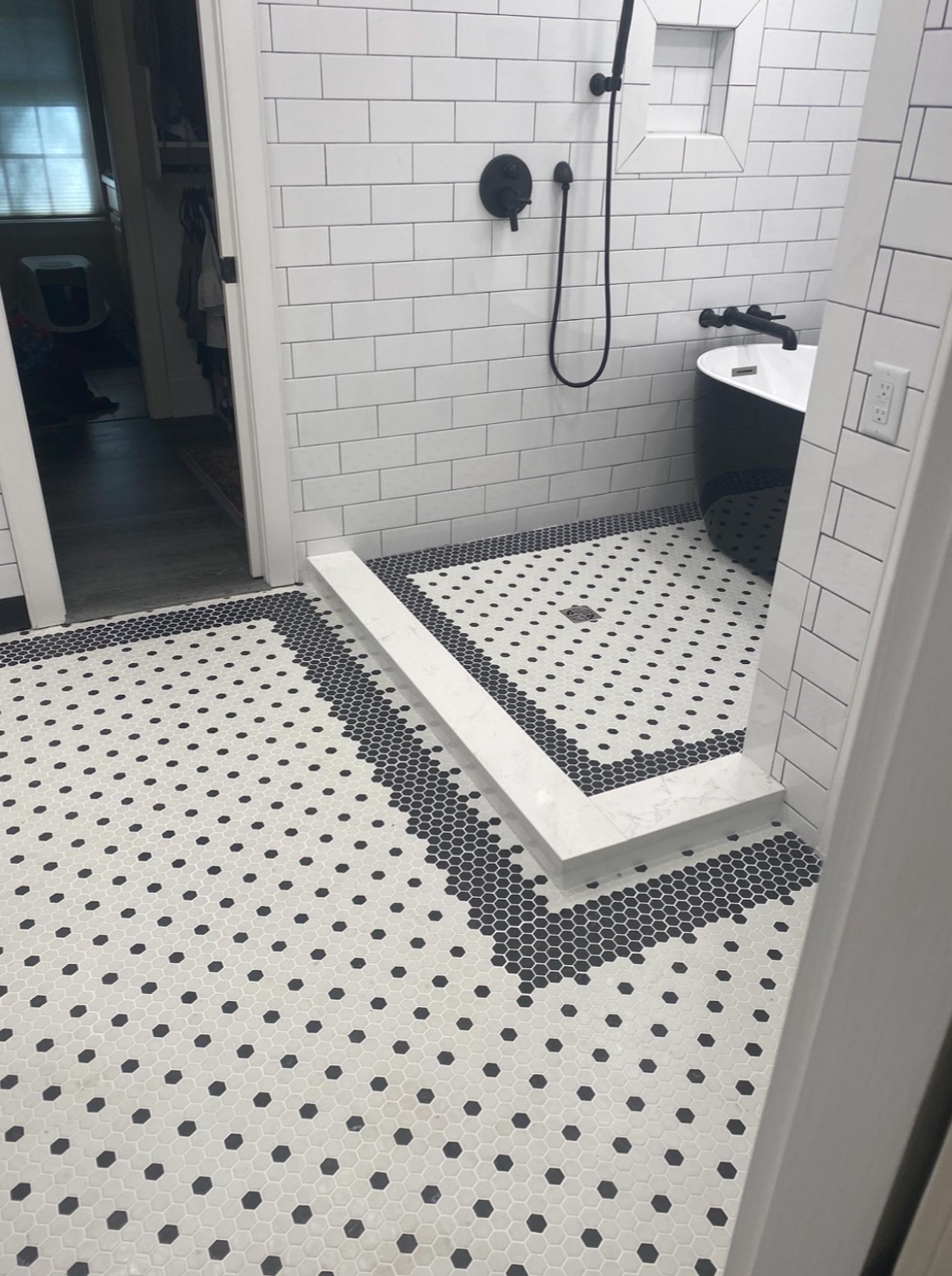 Black-and-white tiled bathroom with a shower, toilet, and open doorway