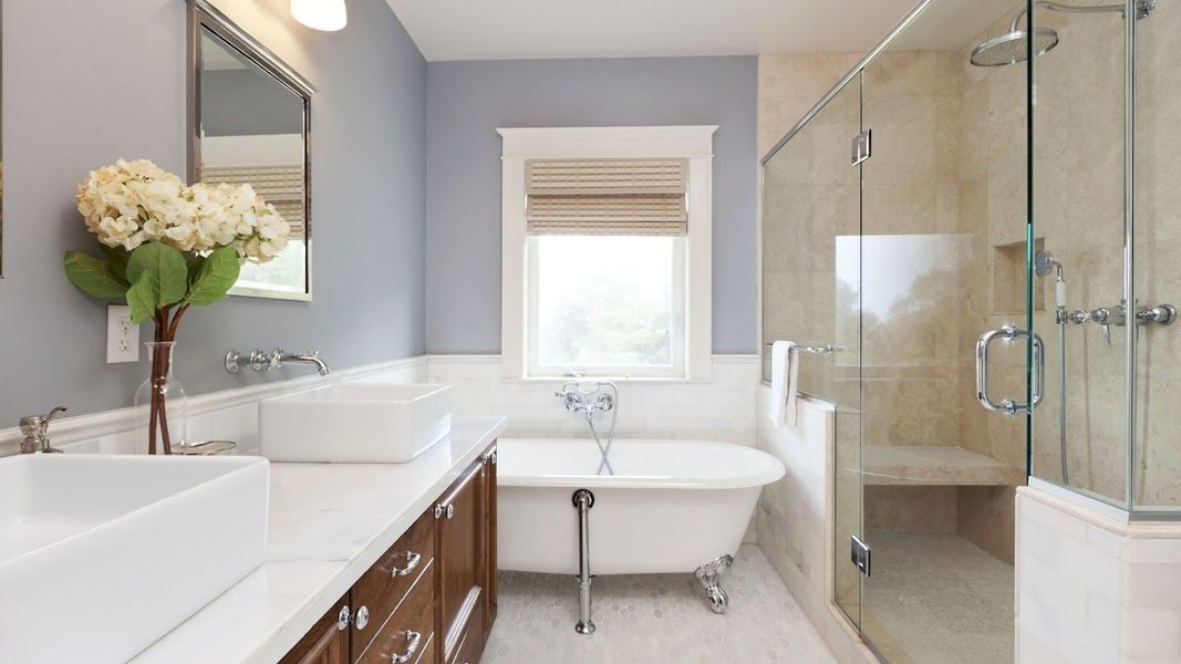 Elegant bathroom with a clawfoot tub, glass shower, and blue-gray walls.