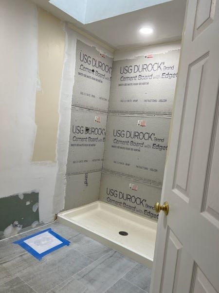 Bathroom renovation in progress: cement board walls installed around shower, ready for tiling.